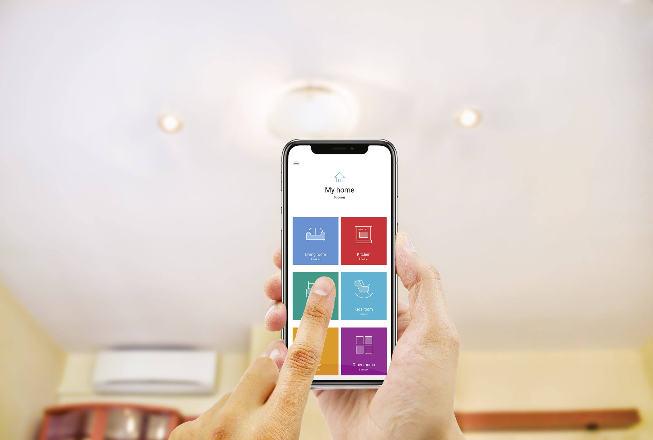 Eine Person nutzt eine Smart-Home-App auf einem Smartphone, um das Licht in einem Raum mit Deckenlampe zu steuern.