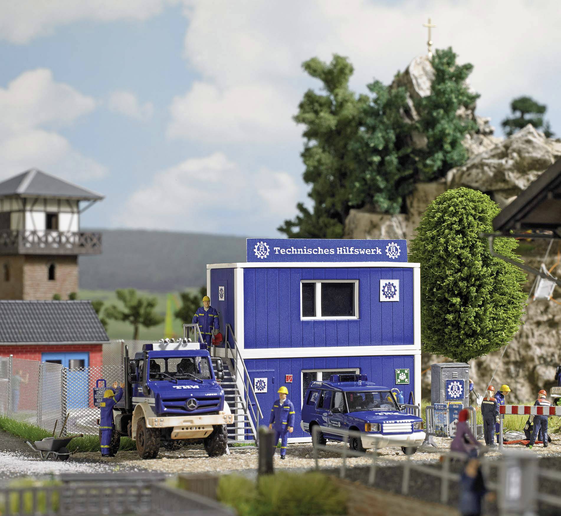 Technische Hilfseinheit in Miniatur: Modelle von Fahrzeugen und Containern vor einer Wache, mit Figuren in Uniform bei der Arbeit.