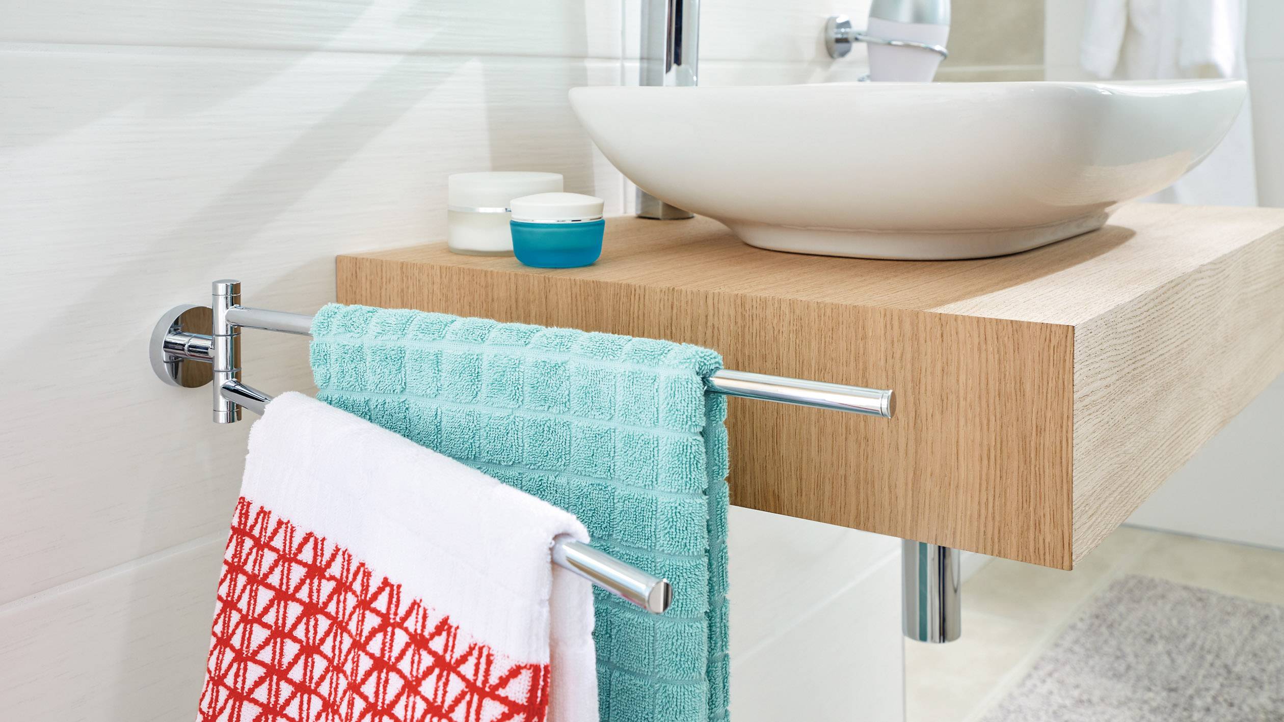 Ein modernes Badezimmer mit einem Holzwaschbecken, blauem und rotem Handtuch am Halter unter dem Becken.