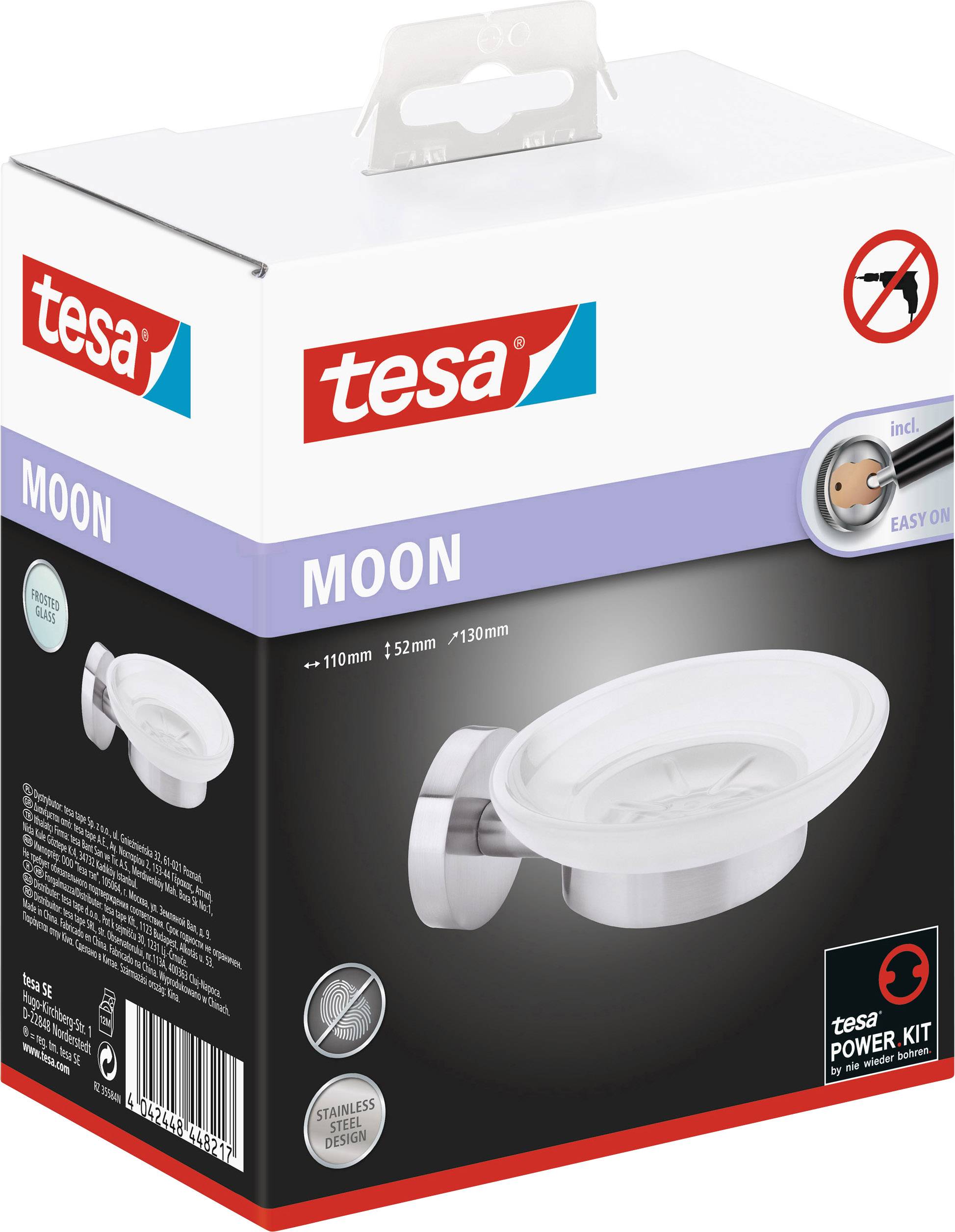 Eine rechteckige Verpackung mit dem Logo 'tesa' zeigt eine Edelstahl-Seifenschale. Text auf der Verpackung: 'MOON', 'Stainless Steel Design'.