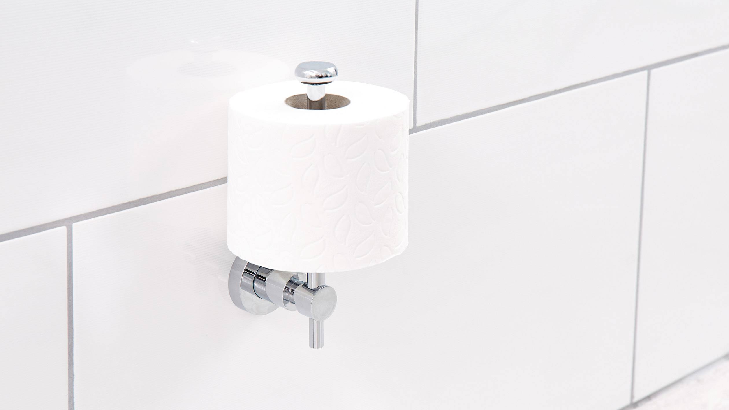 Toilettenpapierrolle auf einem Halter an einer gefliesten Wand befestigt.