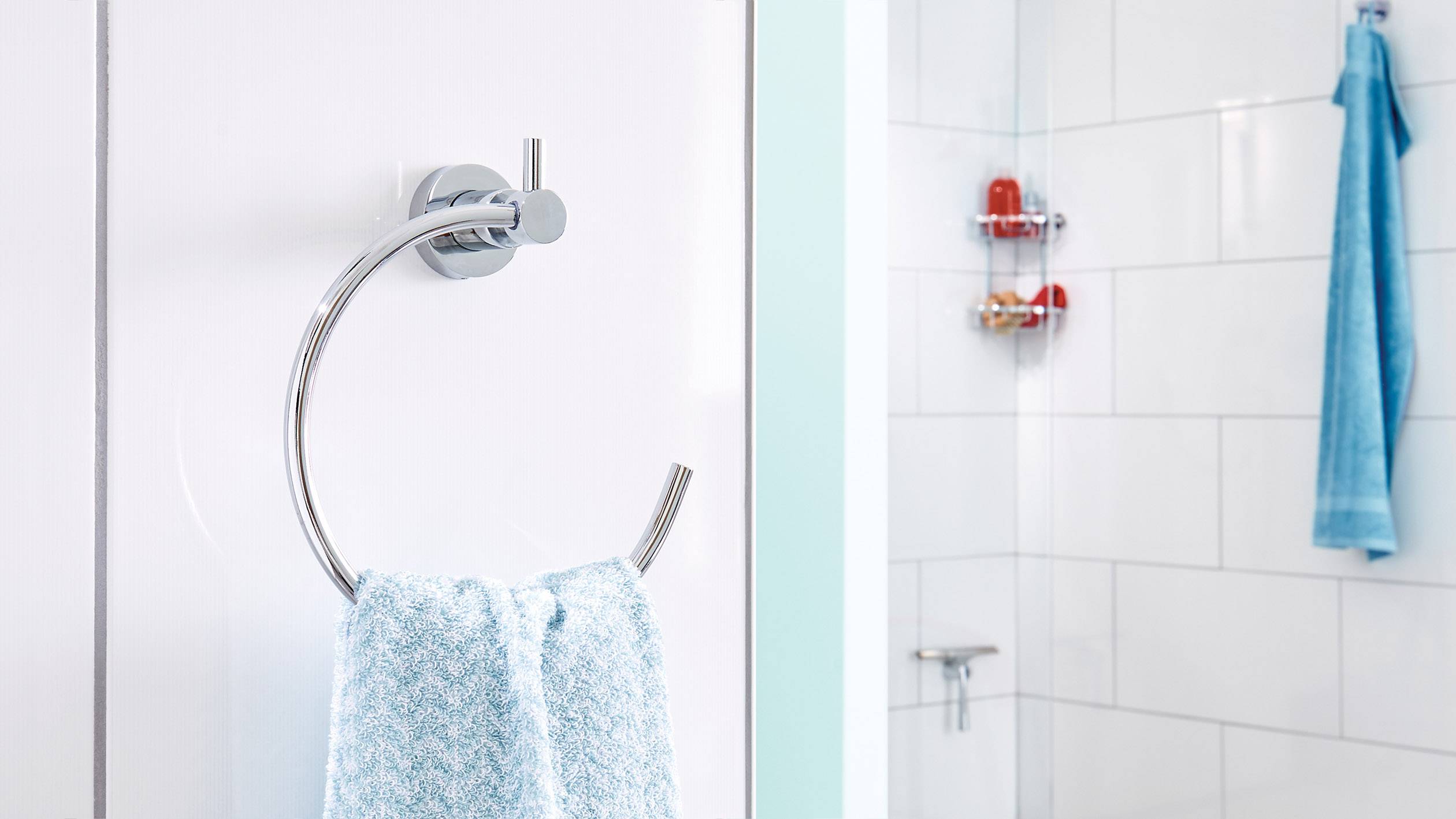 Handtuchhalter an der Wand mit blauem Handtuch; im Hintergrund eine Duschkabine mit Toilettenartikeln und blauem Handtuch.