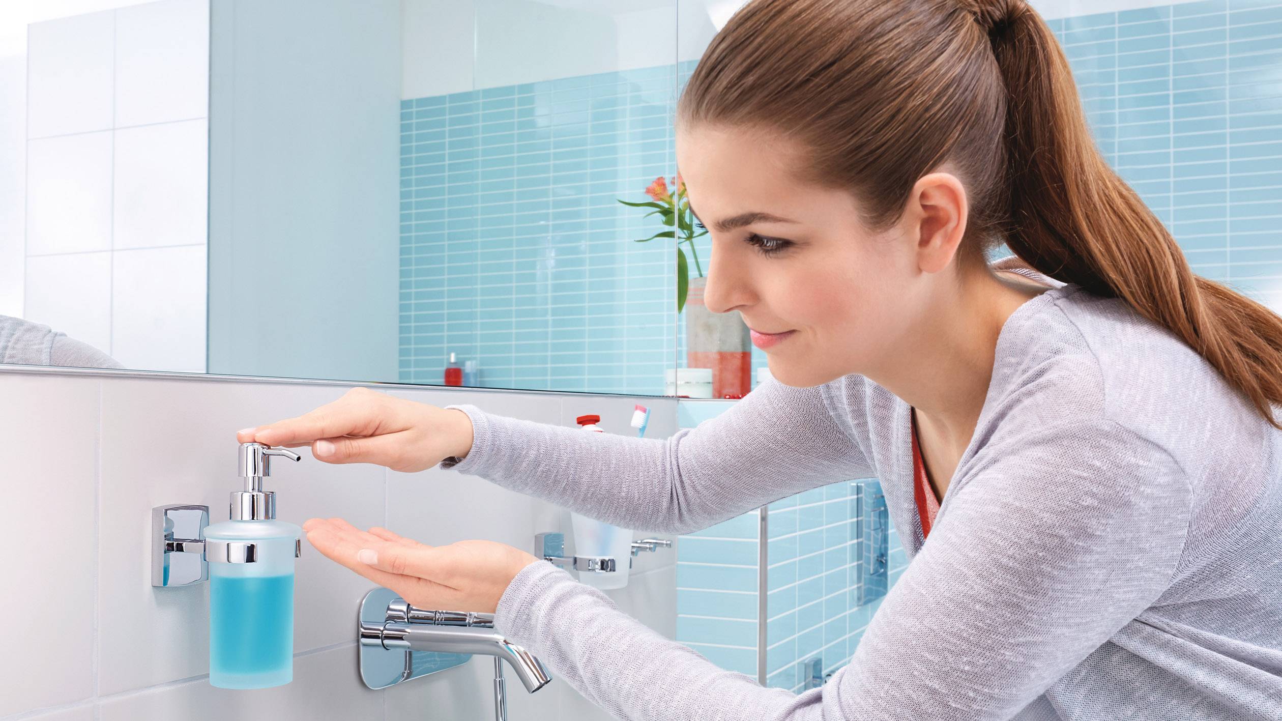 Eine Frau drückt den Seifenspender in einem modernen Badezimmer. Sie hält eine Hand unter den Spender, um Seife herauszupressen.