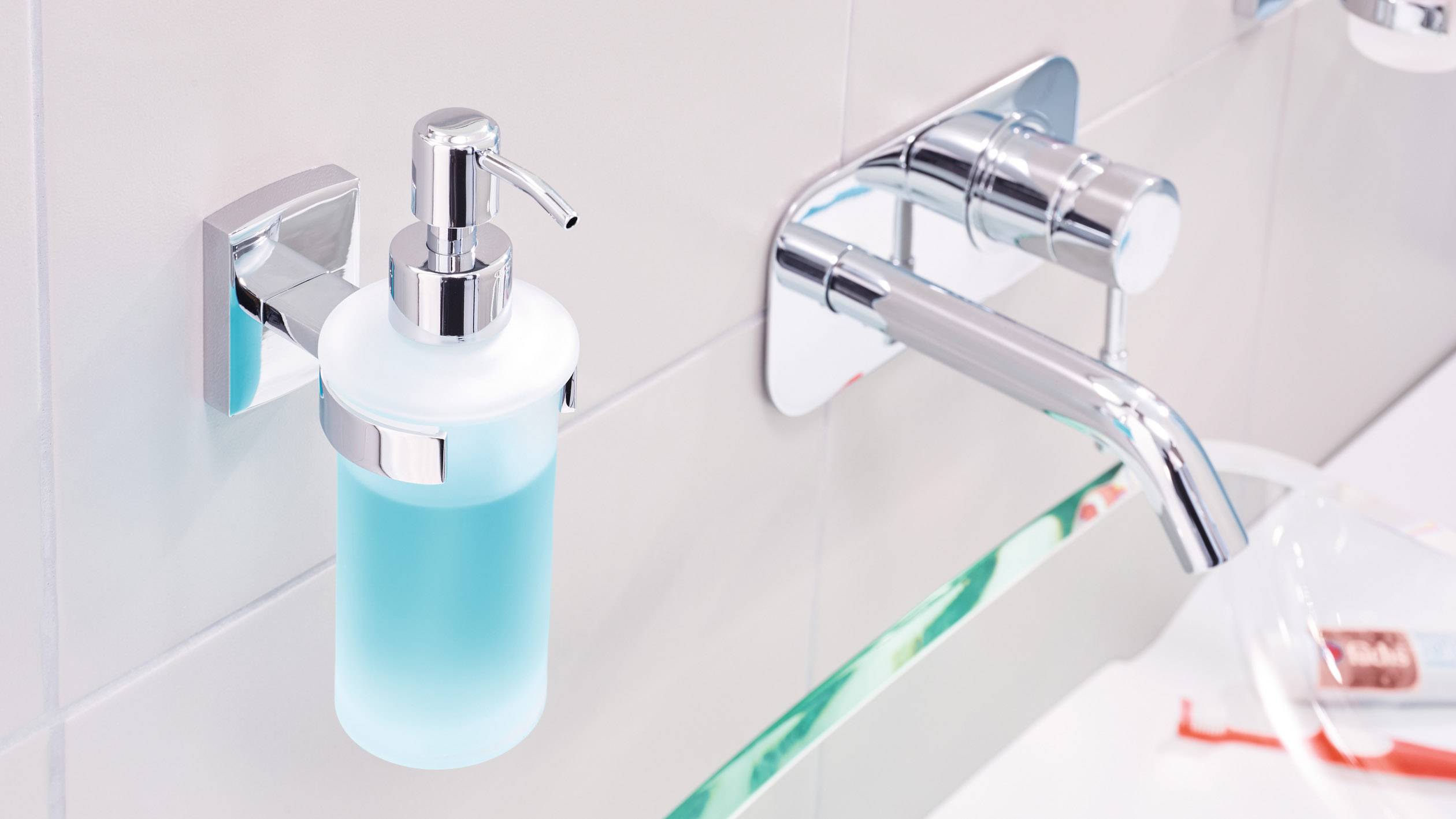 Seifenspender mit blauem Flüssigseife an gefliester Wand neben glänzendem Wasserhahn in moderner Badezimmerumgebung.