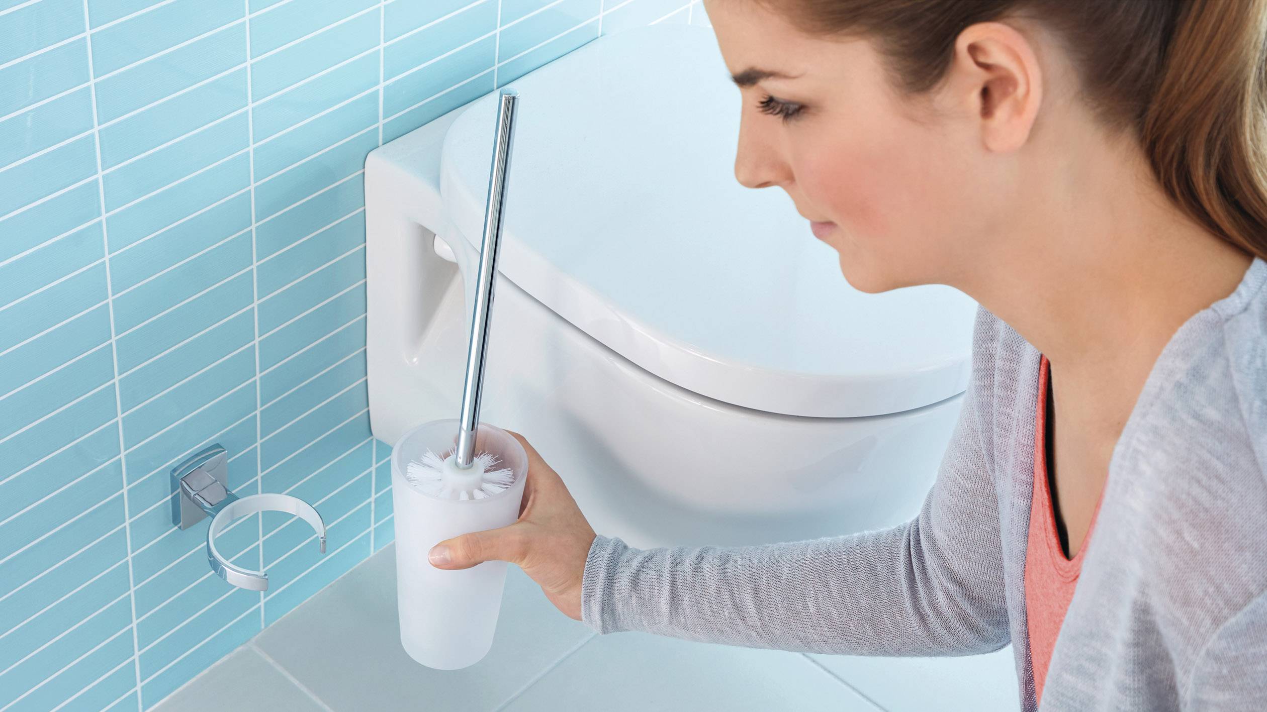 Eine Person reinigt eine Toilette mit einer Toilettenbürste.