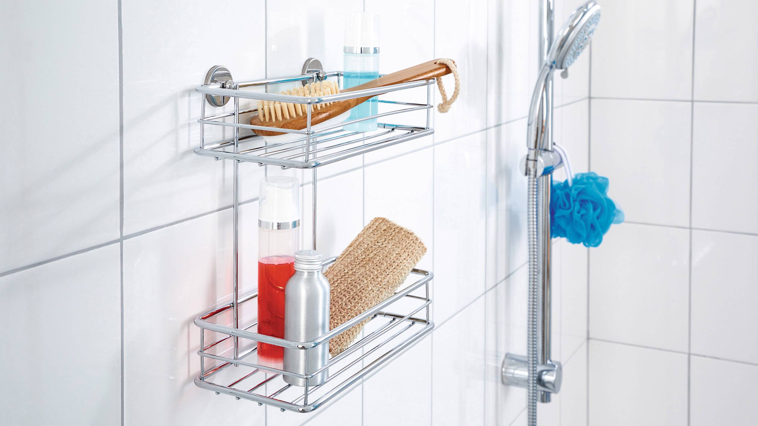 Duschregal im Badezimmer mit Duschgel, Shampoo, Bürste und Schwamm auf Fliesenwand neben einer Duschbrause.