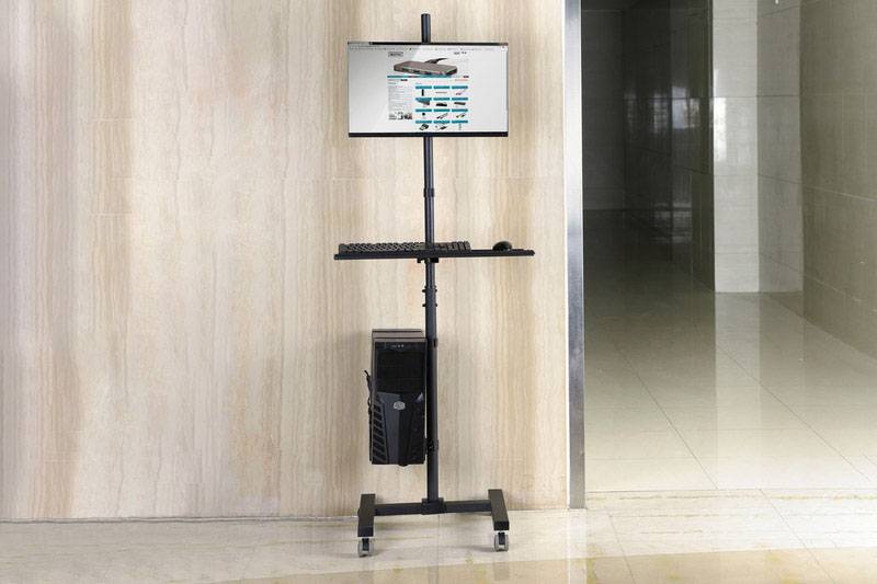Ein tragbarer Computerarbeitsplatz mit Monitor, Tastatur und Computergehäuse auf Rädern steht in einem Büroflur.