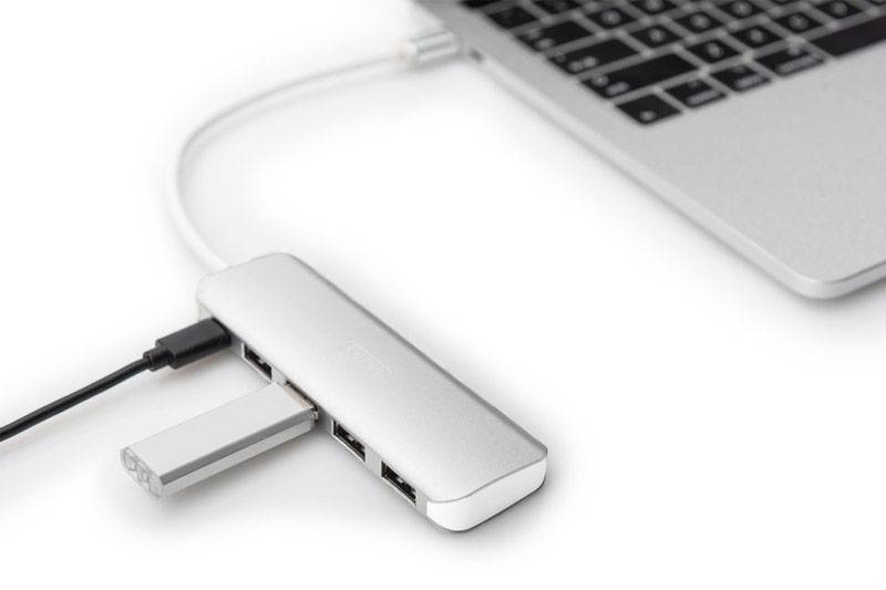 Ein Laptop ist über ein Adapter-Dock mit mehreren USB-Anschlüssen verbunden. Zwei Geräte sind am Dock angeschlossen.
