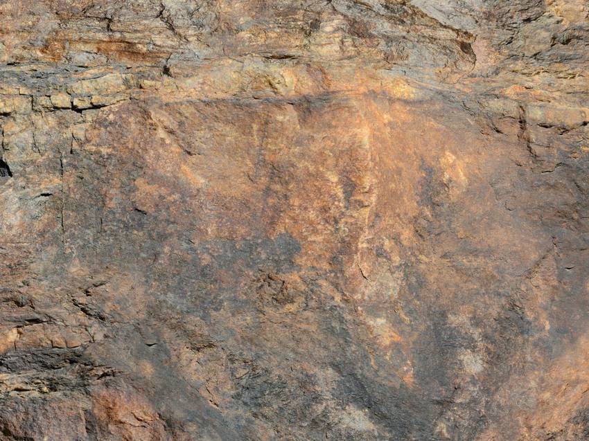 Felsige Oberfläche mit erdigen, rostfarbenen Tönen und verschiedenen Texturen. Ideal zur Darstellung von natürlichen Materialien.