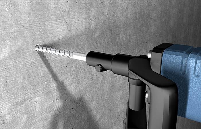 Ein elektrischer Bohrer mit einem Spiralförmigen Bohrer bohrt in eine Betonwand. Der Bohrer ist blau und schwarz.