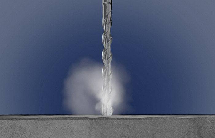 Eine Metallbohrmaschine erzeugt Staub, während sie in eine Oberfläche bohrt.