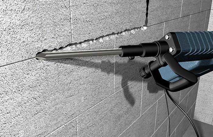Ein blauer elektrischer Meißel wird verwendet, um eine gerade Linie in eine graue Betonwand zu schneiden.