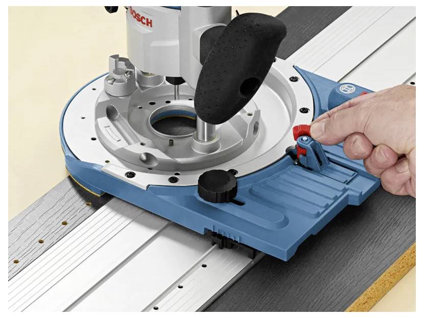 Eine Hand stellt einen Hebel an einem blau-silbernen Holzbearbeitungsrouter ein, der an einer Führungsschiene befestigt ist und zum präzisen Schneiden und Formen von Holz verwendet wird.