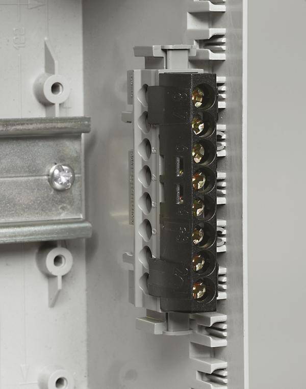 Eine Nahaufnahme eines elektrischen Verteilerkastens mit einer schwarzen Klemmenleiste auf einer grauen Metallplatte.