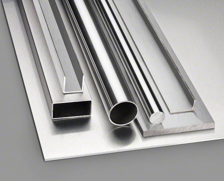 Metallprofile aus Edelstahl: quadratisch, rechteckig und rund, liegen auf einem Metallblech. Sie zeigen die Vielfalt industrieller Metallformen.