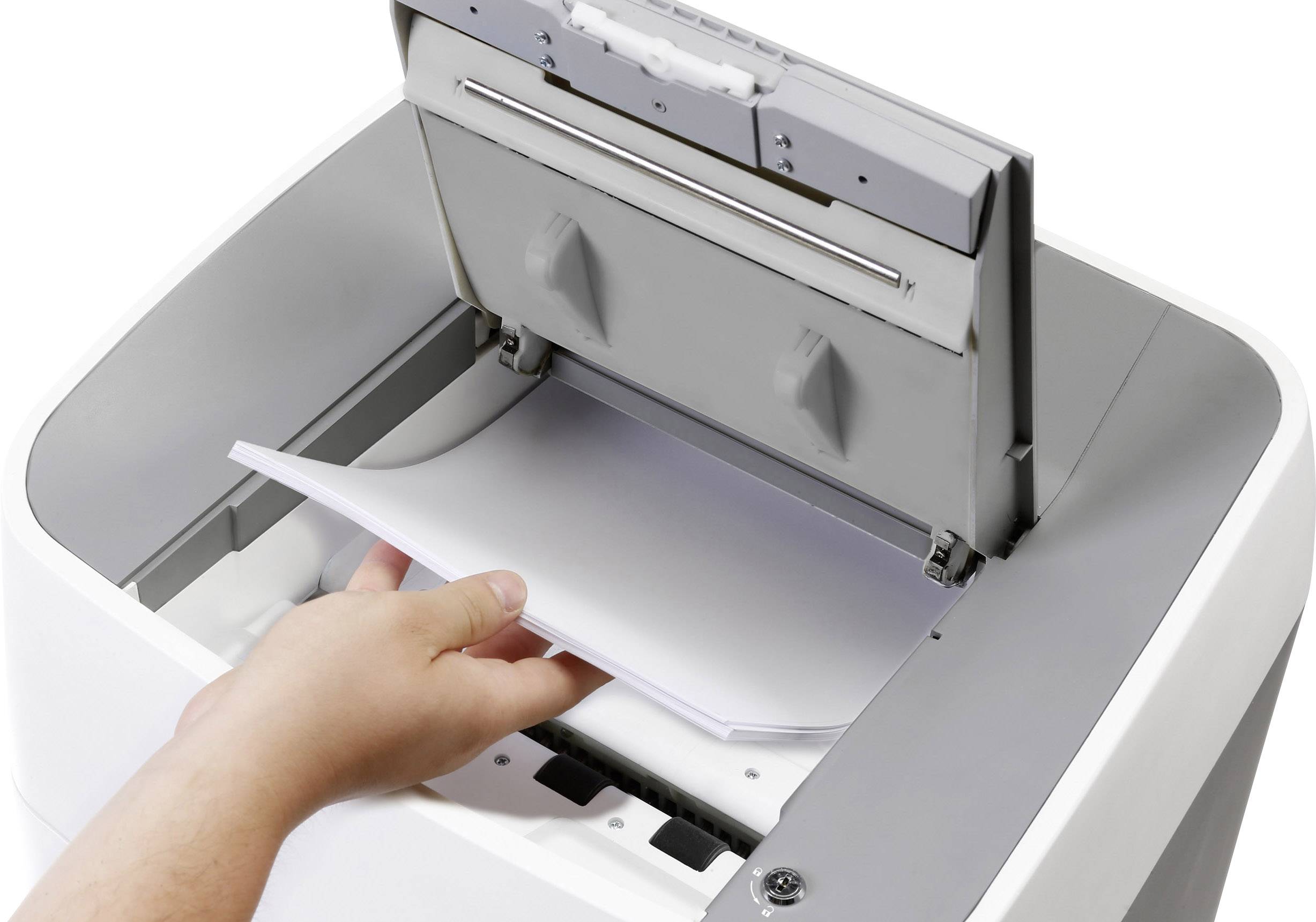 Eine Hand legt Papier in einen Drucker ein. Der Drucker ist geöffnet und bereit, Papier zu laden.