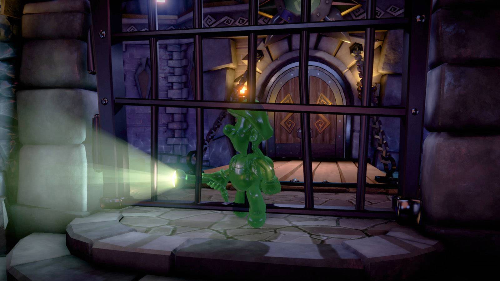Eine grüne geleeartige Figur mit Taschenlampe steht vor einem verschlossenen Gittertor in einem dunklen Steingang.