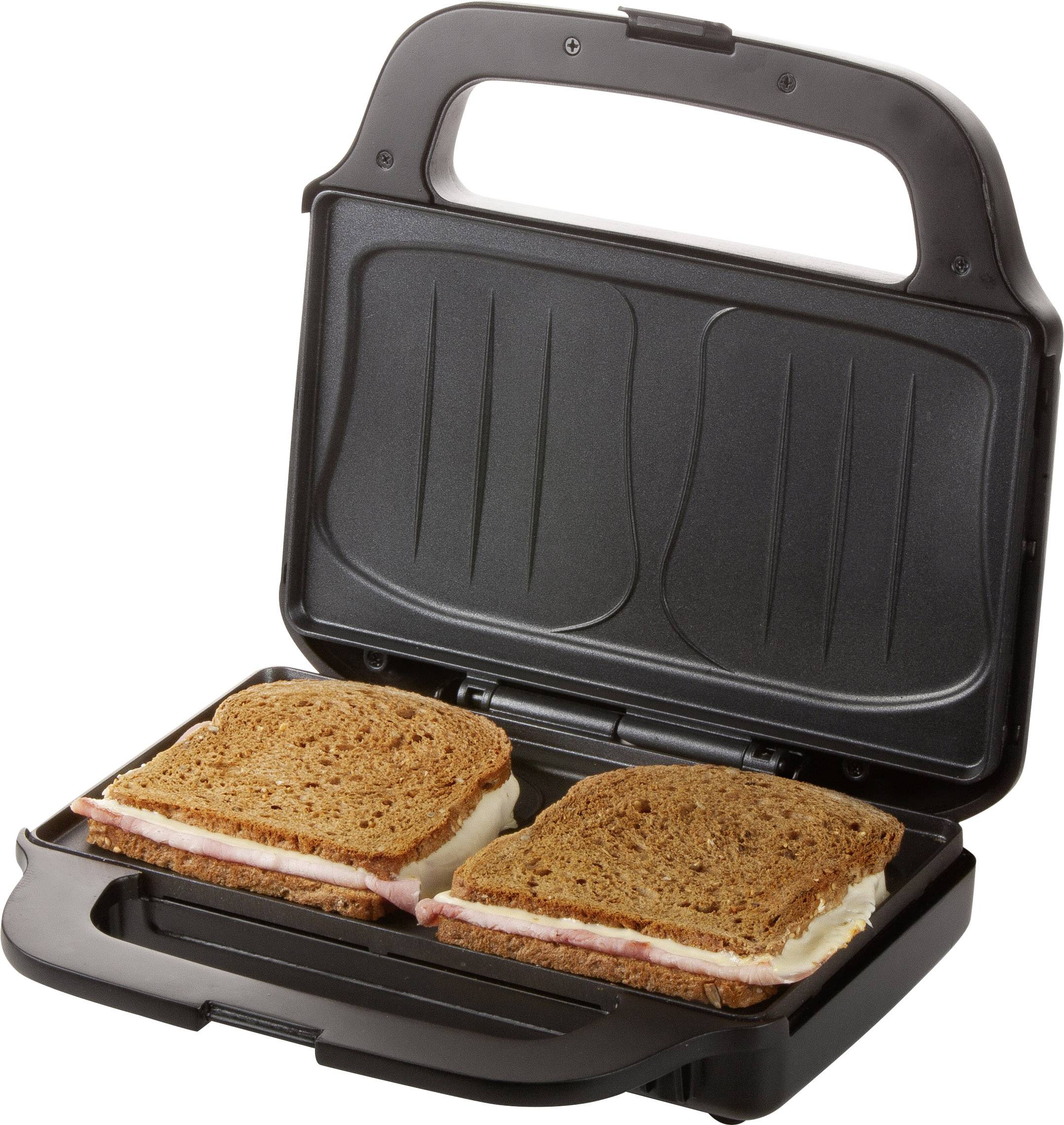 Ein Sandwichmaker mit zwei geschlossenen Toastsandwiches aus dunklem Brot, gefüllt mit Schinken und Käse, bereit zum Grillen.