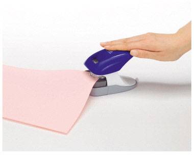 Eine Hand, die mit einem blauen Hefter ein pinkfarbenes Blatt Papier auf einem Tisch zusammenheftet.