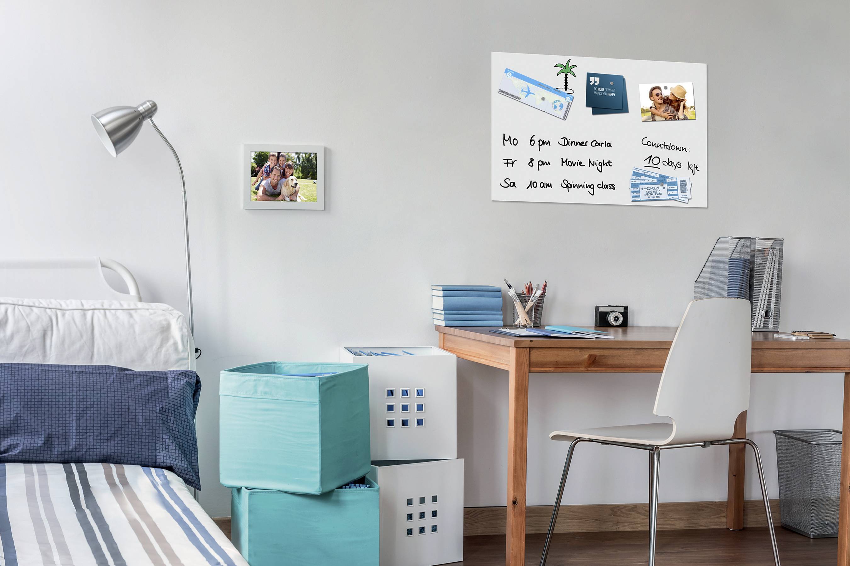 Ein helles Schlafzimmer mit einem Schreibtisch, auf dem Notizbücher liegen. An der Wand hängt eine Pinnwand mit Fotos und Notizen.