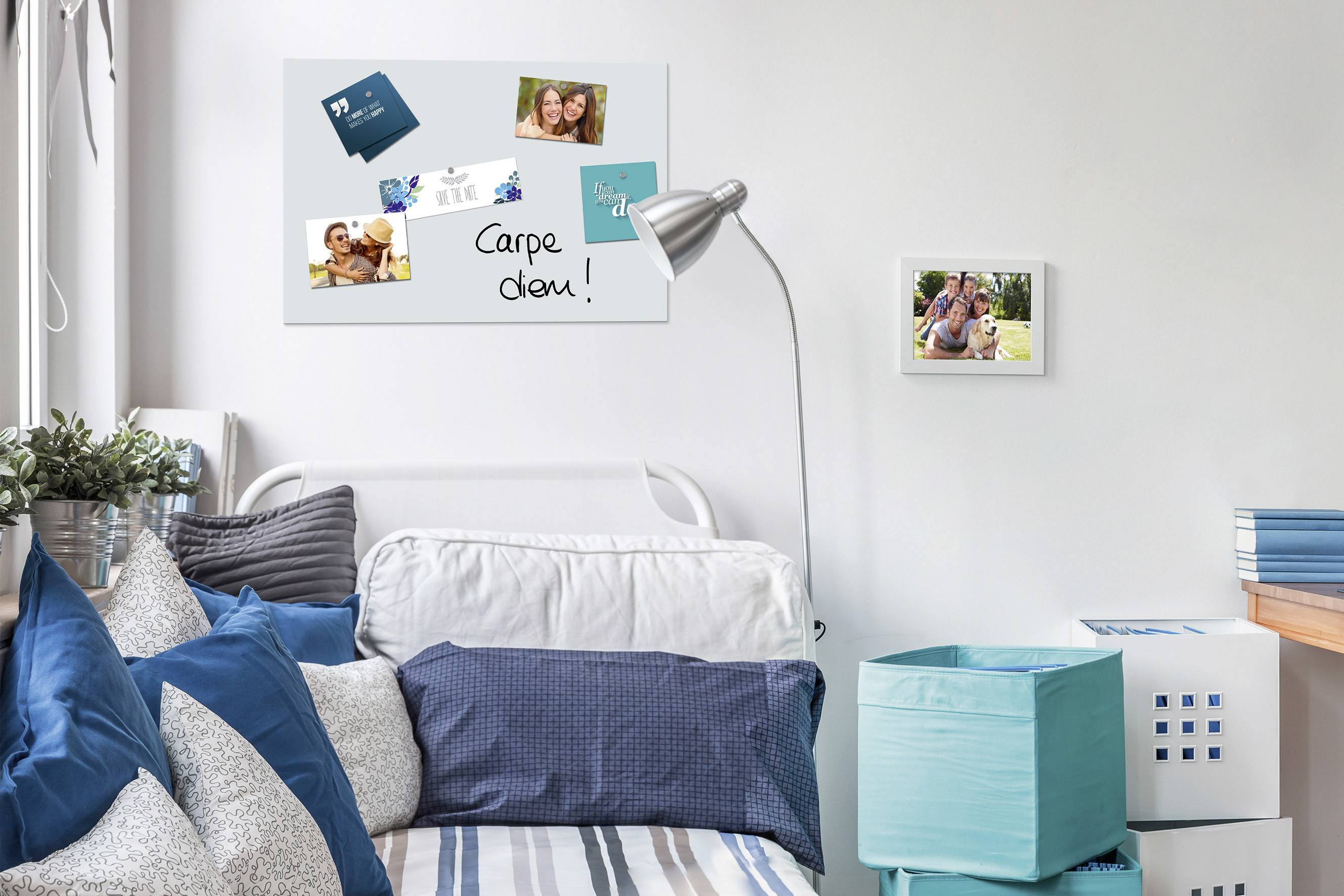 Ein gemütliches Schlafzimmer mit weißem Bett, blauen Kissen und Wandbildern. Eine Schreibtischlampe leuchtet ein inspirierendes Zitat: 'Carpe diem!'.