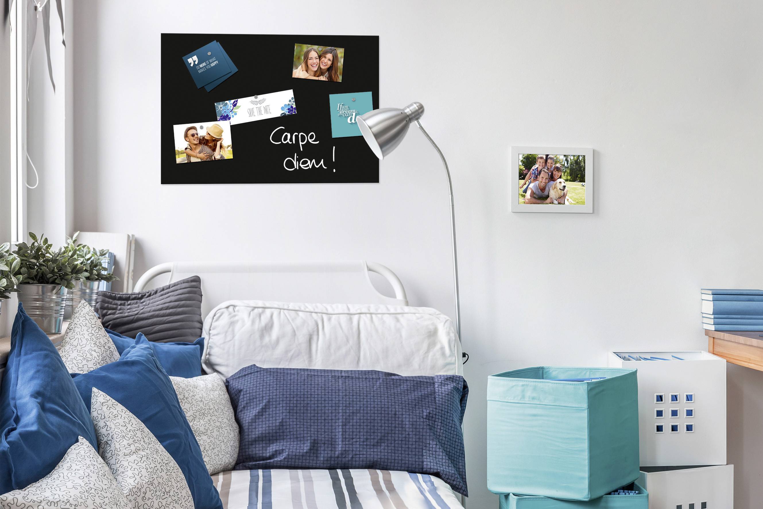 Schlafzimmer mit blau-weißer Bettwäsche, Wandtafel mit Fotos und dem Text 'Carpe diem!', daneben ein weiteres Foto an der Wand.