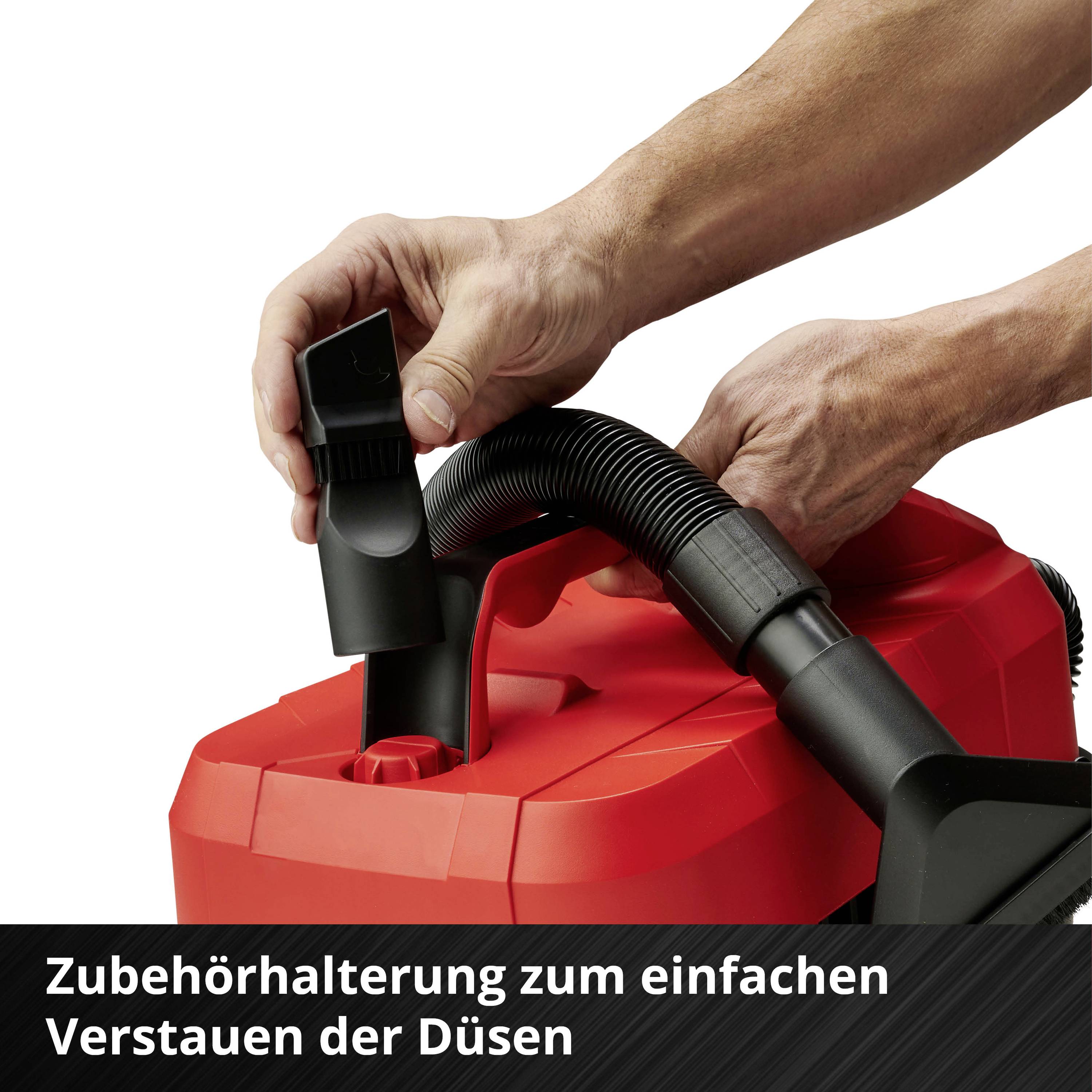 Hände befestigen eine Düse an einem roten Staubsauger mit der Beschriftung 'Zubehörhalterung zum einfachen Verstauen der Düsen'.