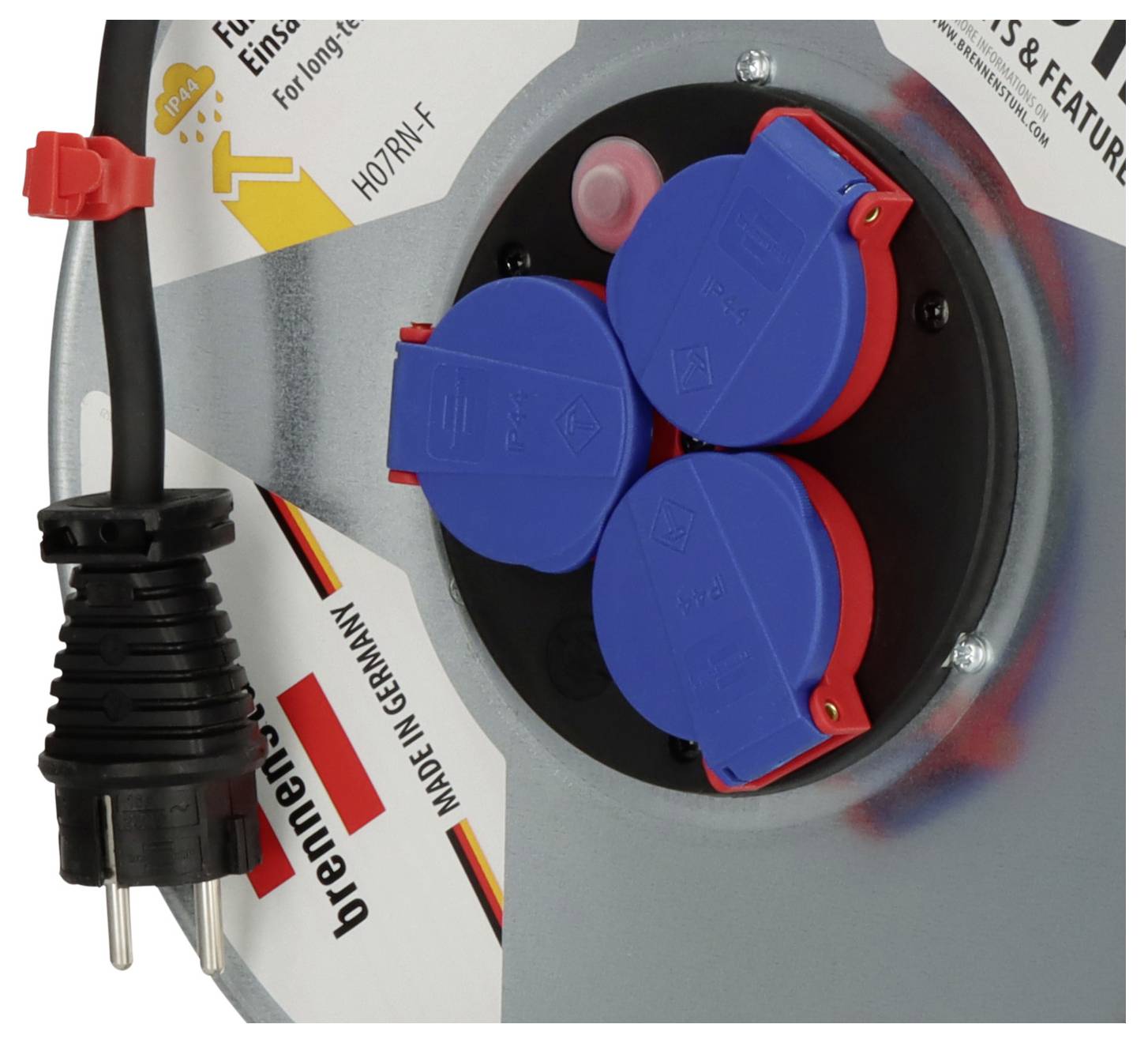 Nahaufnahme eines industriellen Elektroschaltschranks mit einer blauen Dreifach-Steckdose mit roten Abdeckungen und einem angebrachten robustem Stecker auf der linken Seite.