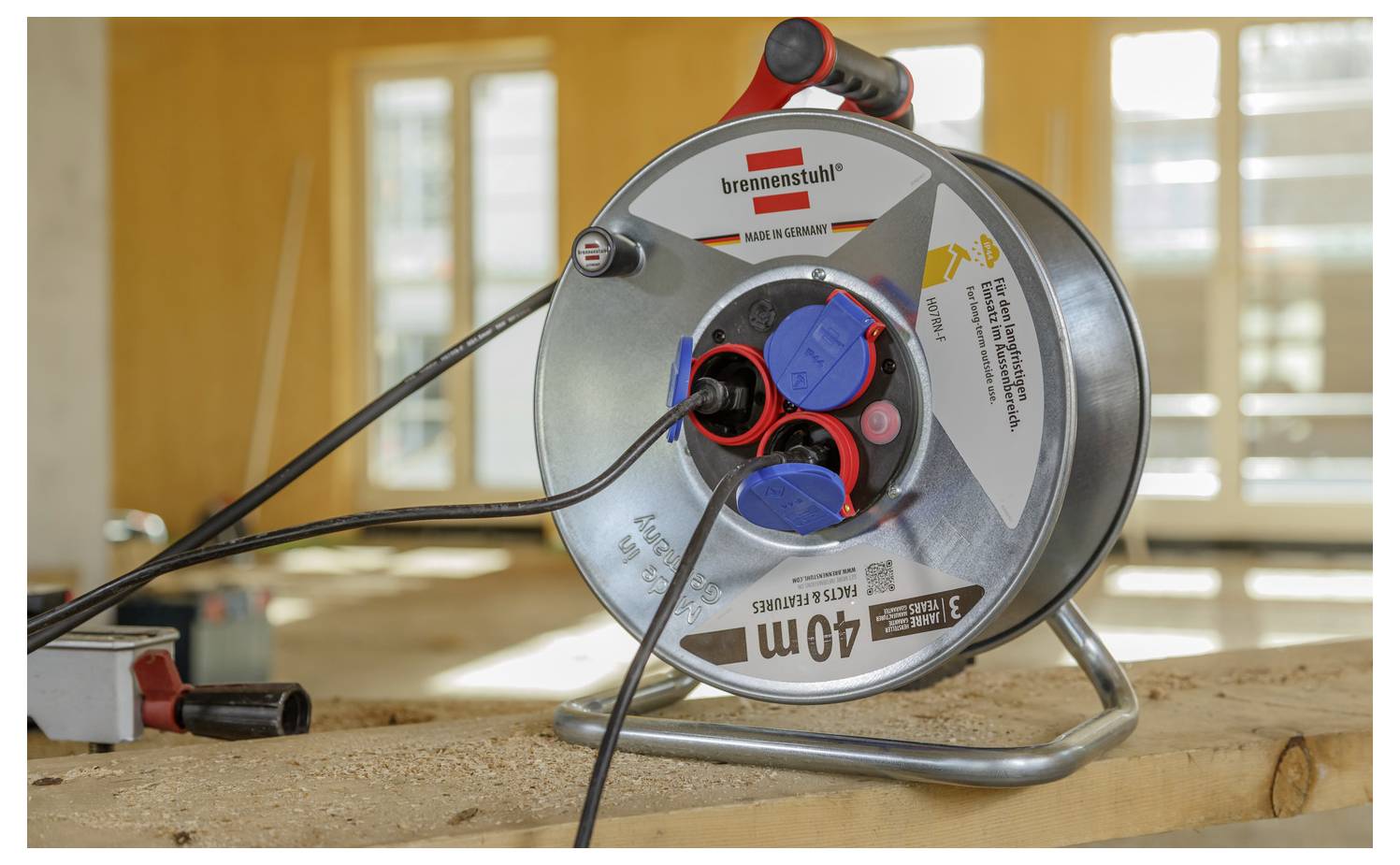 Nahaufnahme einer Brennenstuhl 40m Kabelrolle auf einer Werkbank, mit mehreren angeschlossenen Kabeln und Sonnenlicht im Hintergrund.