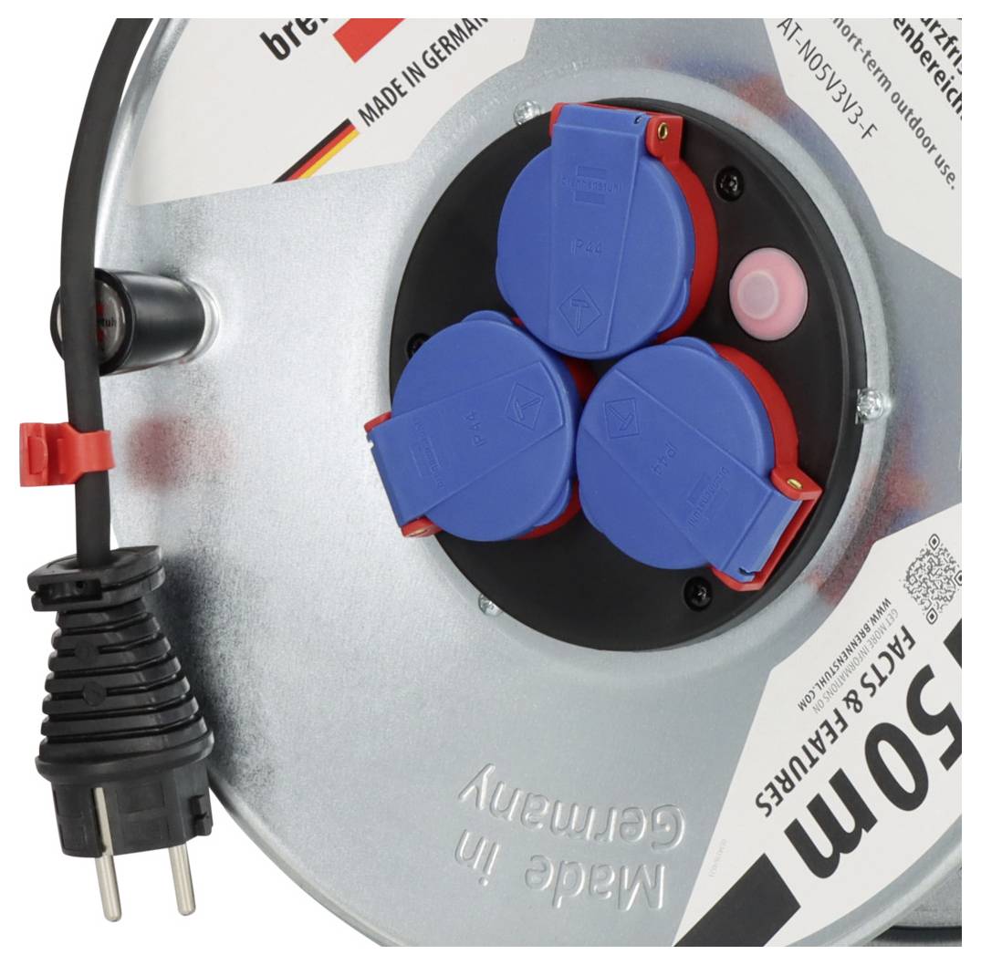 Nahaufnahme einer tragbaren Kabelrolle mit drei blau abgedeckten Steckdosen, einem schwarzen Stromstecker und einem integrierten rosa Knopf auf einer silbernen Spule.