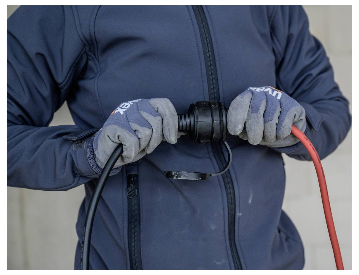 Person in Handschuhen, die zwei elektrische Kabel mit einem schwarzen Adapter verbindet, mit einem roten Kabel und einem schwarzen Kabel