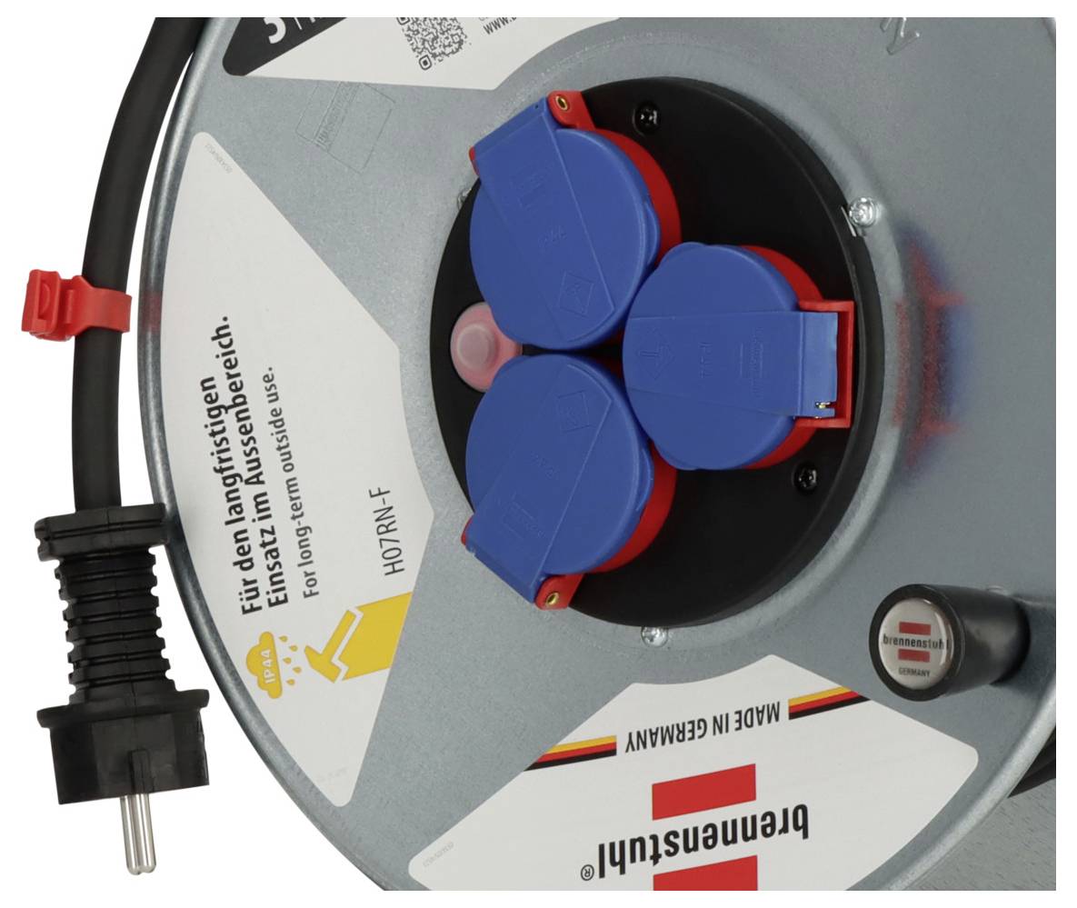 Nahaufnahme einer Brennenstuhl-Kabelrolle mit drei blauen Steckdosenschutzkappen, einem Stromstecker und deutschen Warnetiketten auf dem Gehäuse.