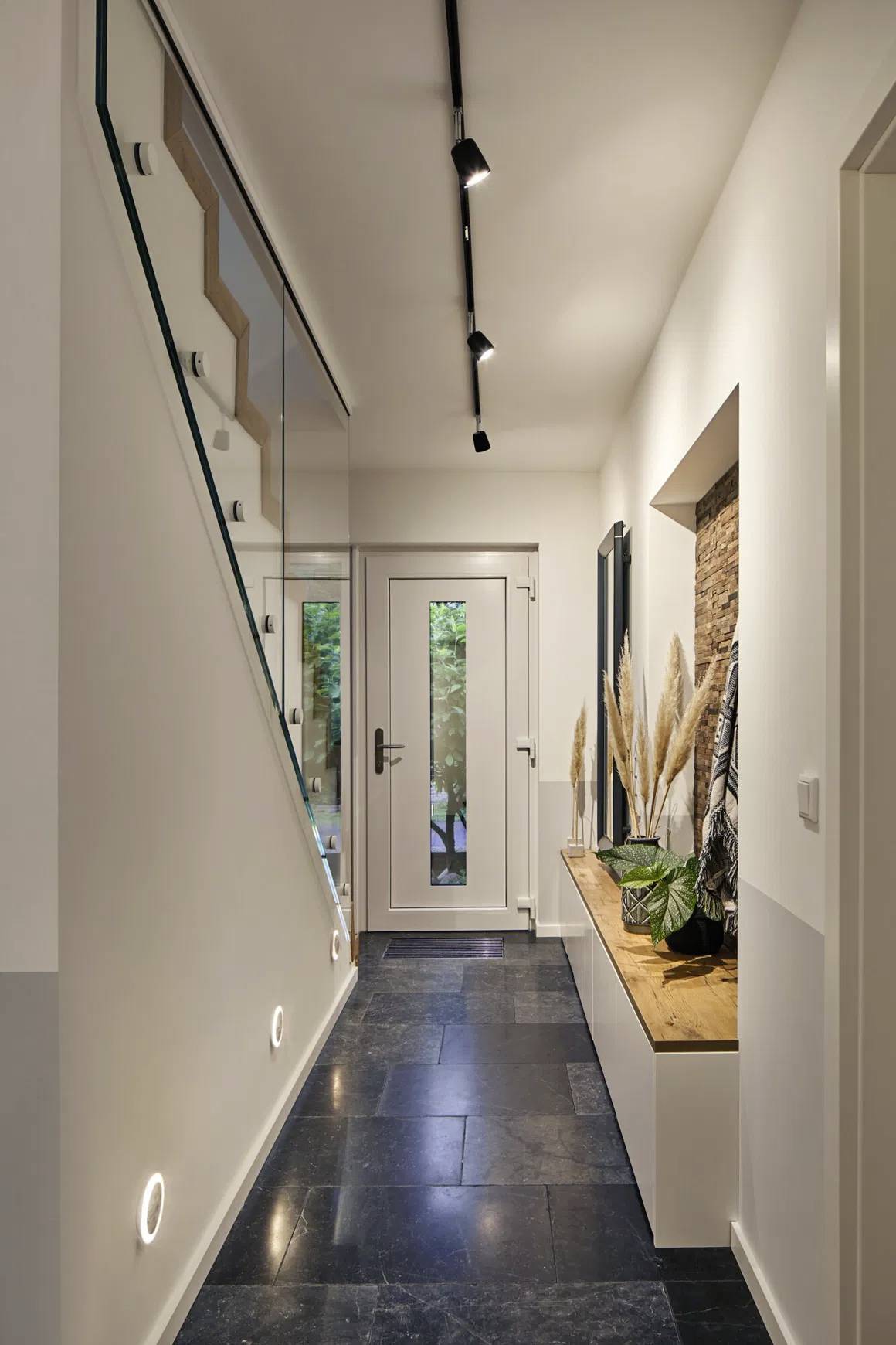 Ein moderner Raum mit Holzboden, grüner Pflanzenwand und Schrank mit Holztüren. Ein Fenster im Dach sorgt für Helligkeit.