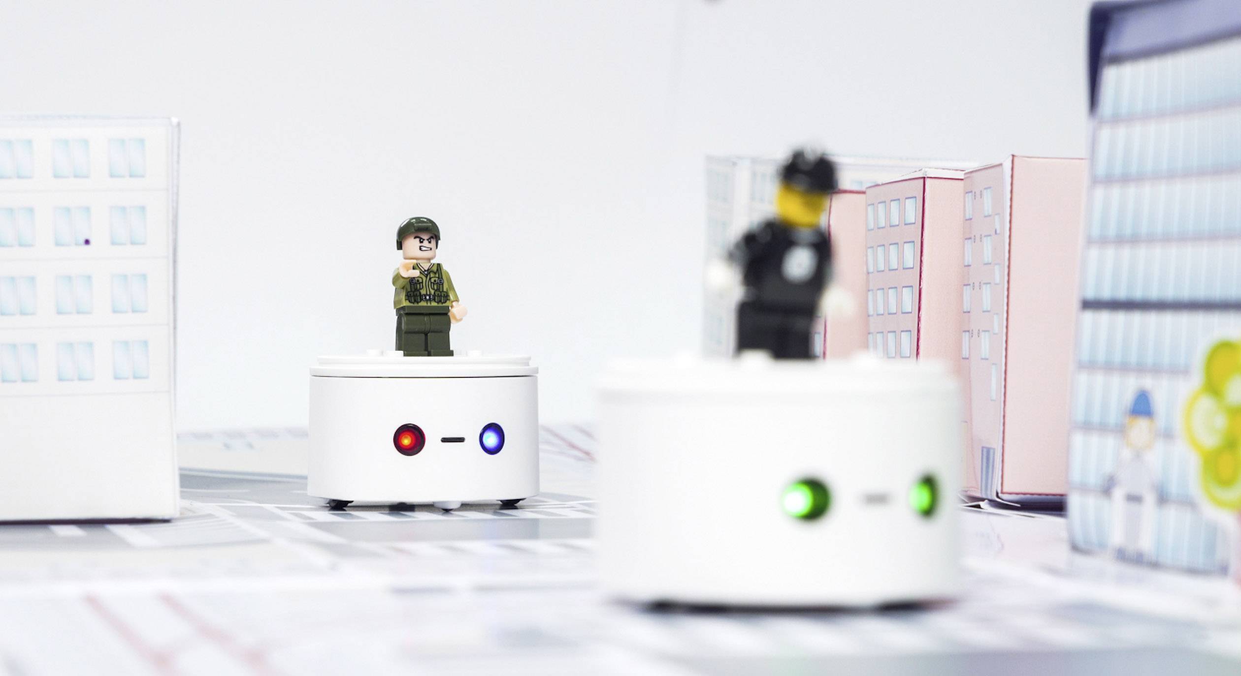 Spielzeugfiguren auf runden Plattformen in einer Miniaturstadt. Eine Figur trägt eine Uniform, die andere eine Polizeiuniform.