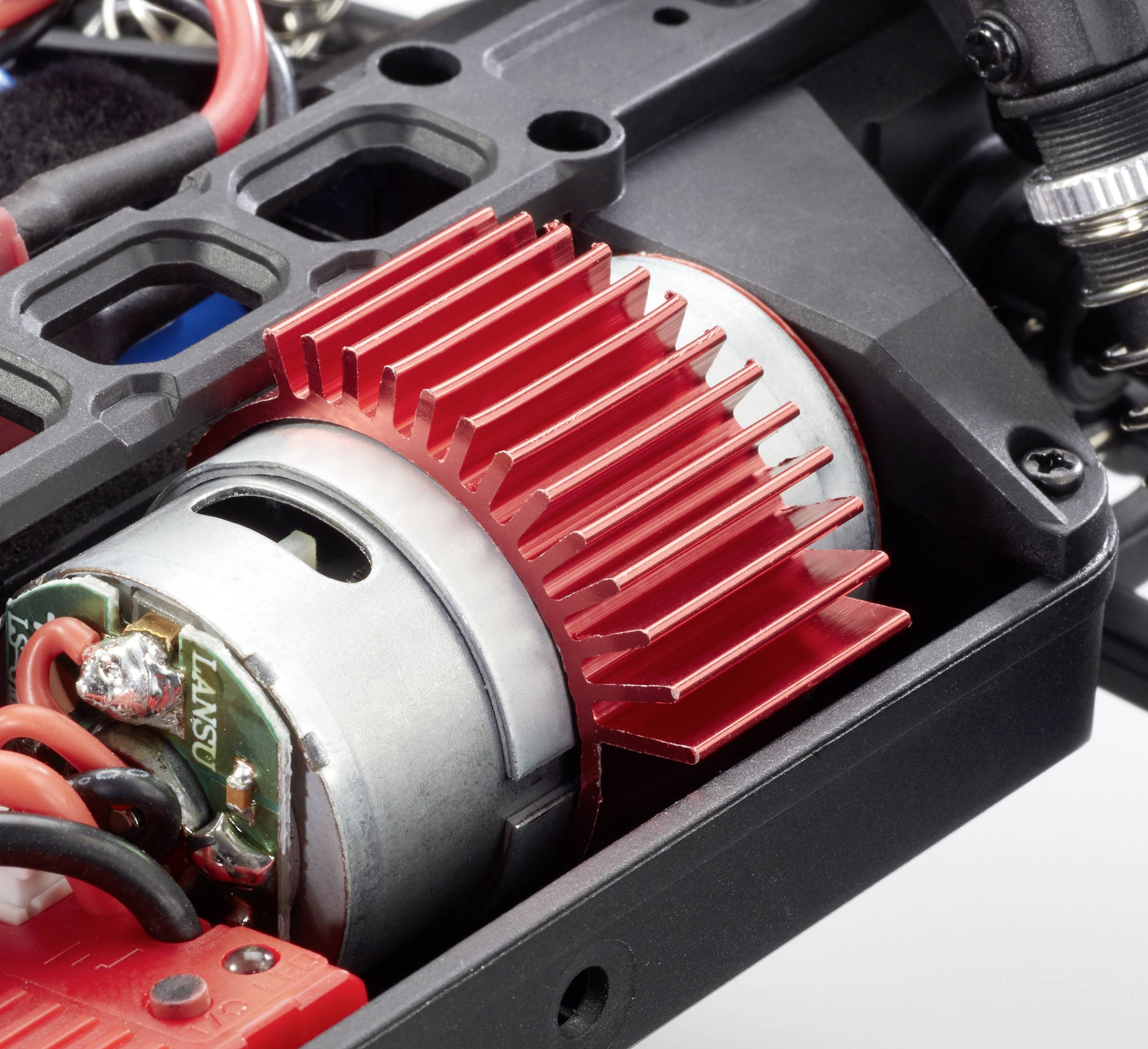 Ein roter Kühlkörper ist auf einem Elektromotor in einem technischen Gerät montiert. Drähte sind mit dem Motor verbunden.