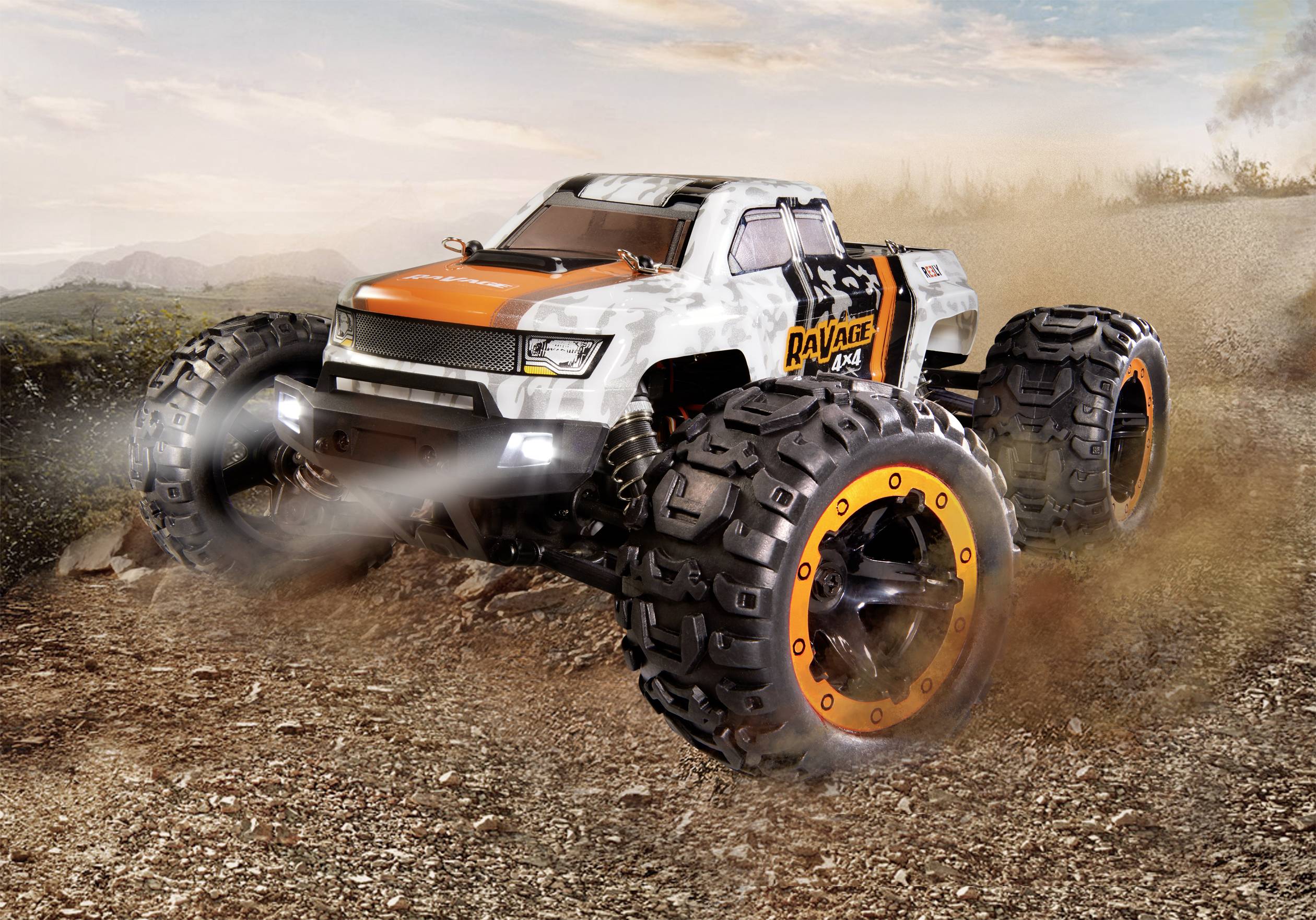 Ein ferngesteuertes Monstertruck-Modell mit großen Reifen fährt über einen staubigen Pfad und wirbelt Schmutz auf.