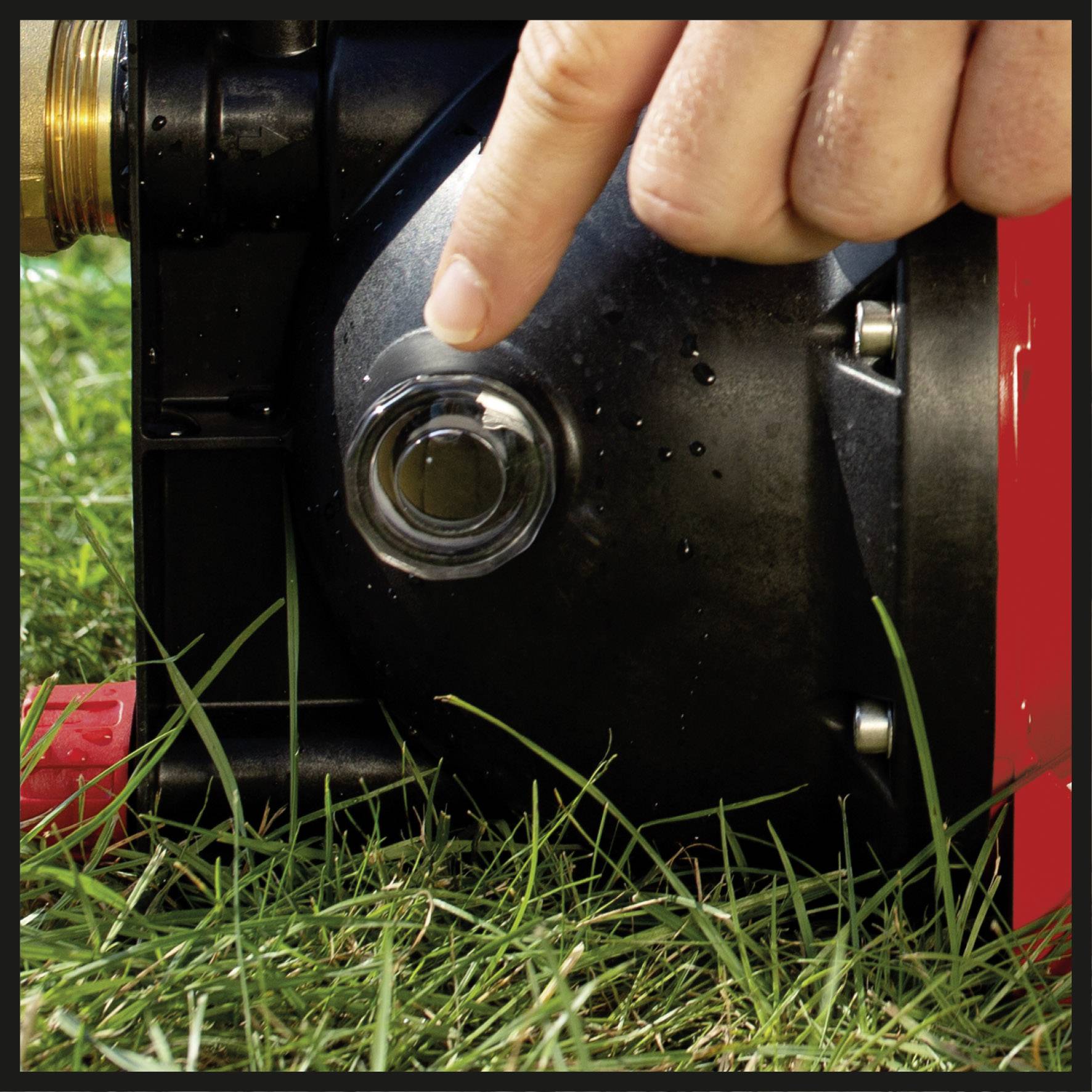 Eine Hand drückt auf einen Knopf an einem Gerät im Garten. Der Fokus liegt auf der Interaktion mit der Technik im Freien.