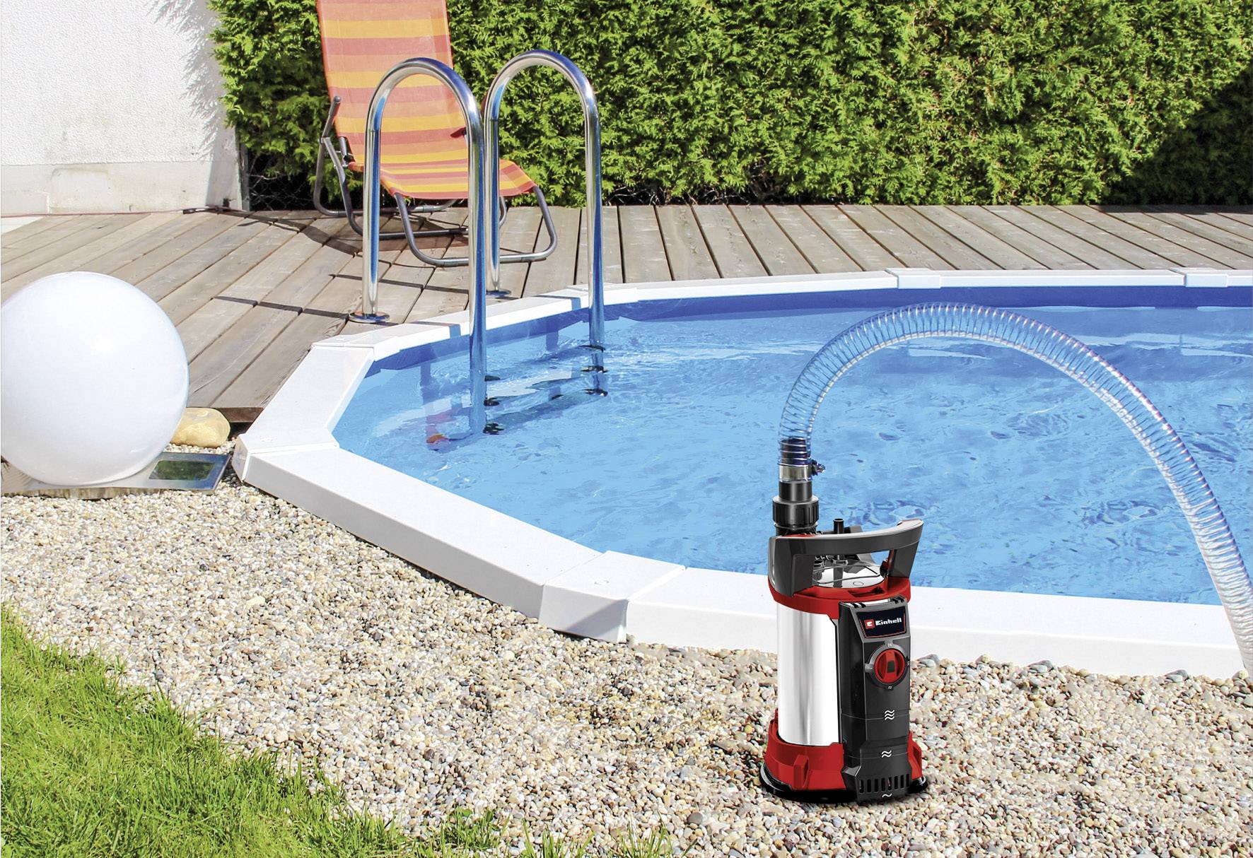 Gartenteichpumpe neben einem gefüllten, runden Pool mit Leiter, umgeben von einer Holzterrasse und einem Liegestuhl.