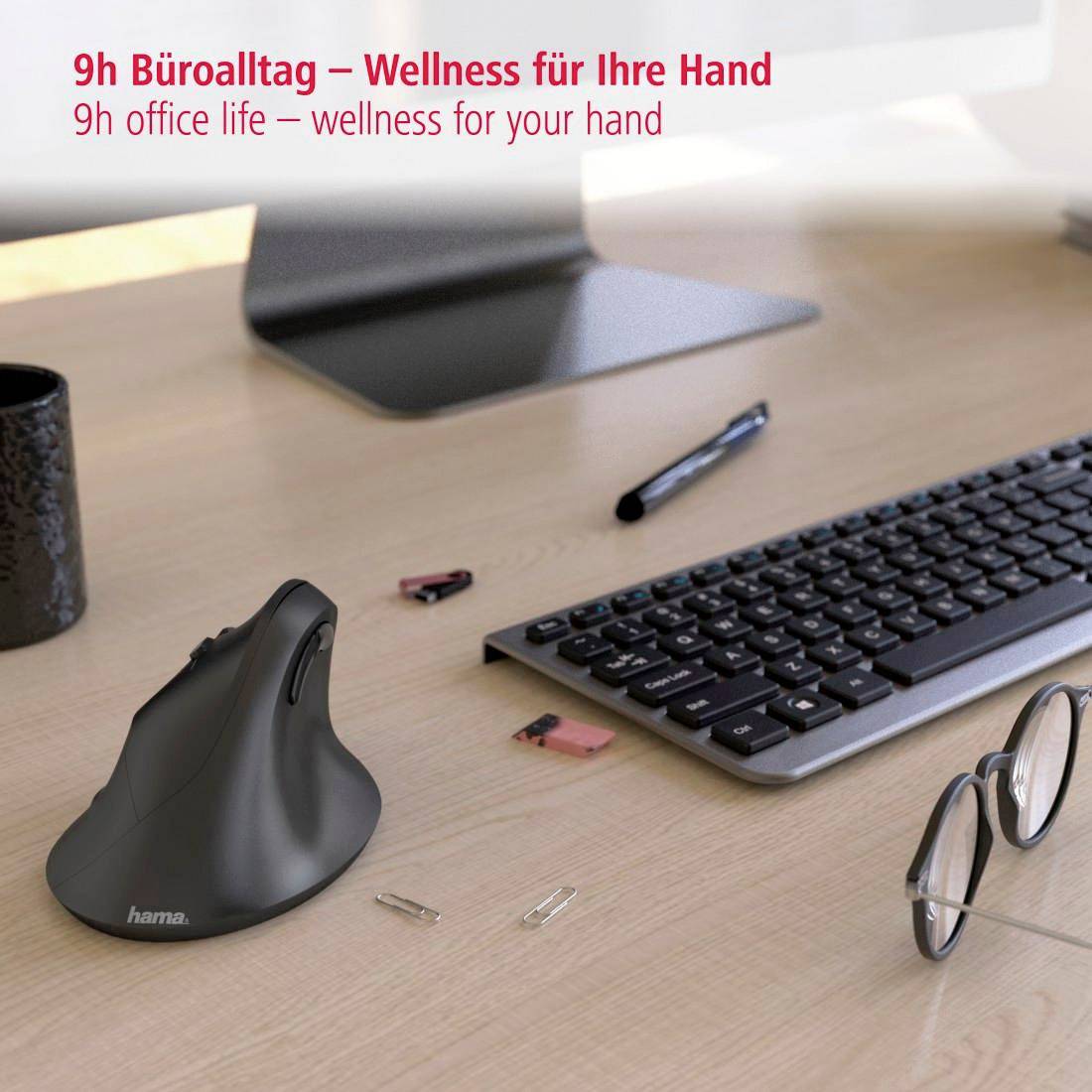 Ergonomische Maus auf Schreibtisch vor einem Monitor, daneben Tastatur und Brille; Text: '9h Büroalltag – Wellness für Ihre Hand'.