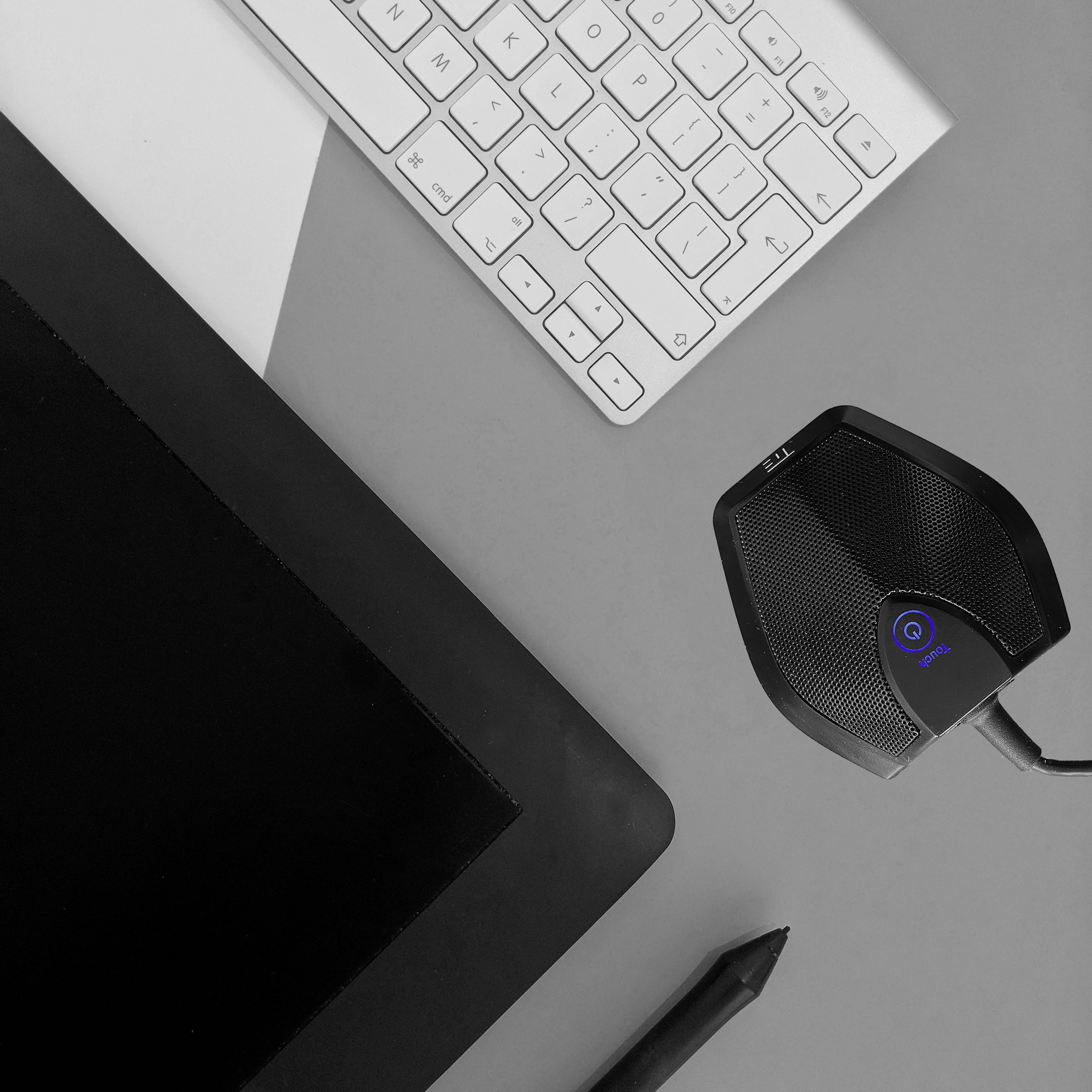 Tastatur, Grafiktablett, Mikrofon und Stift auf einem grauen Schreibtisch angeordnet. Arbeitsbereich für kreative Aufgaben.