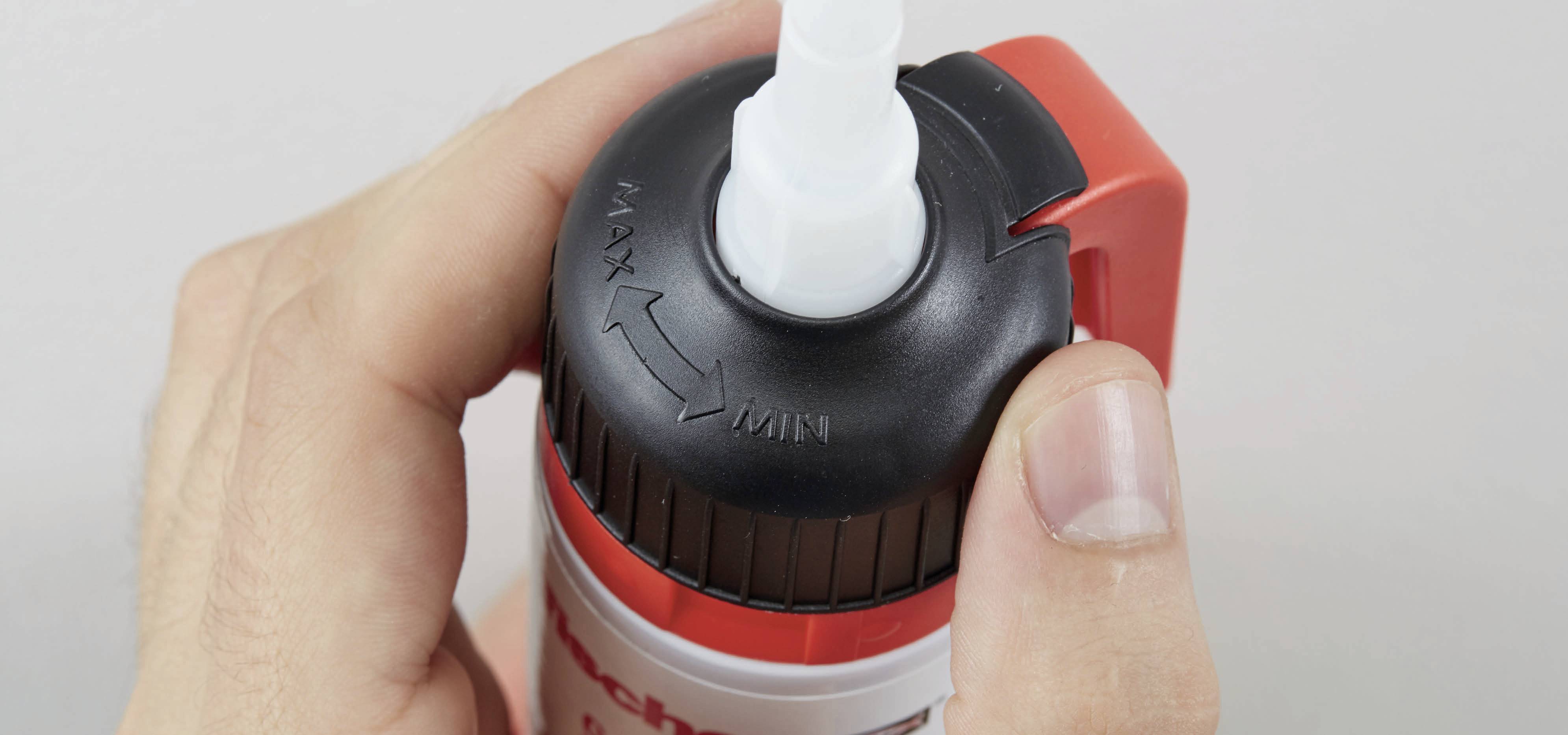 Nahaufnahme einer Hand, die eine Flasche mit Drehverschluss hält; Pfeile zeigen die Richtungen Max und Min.