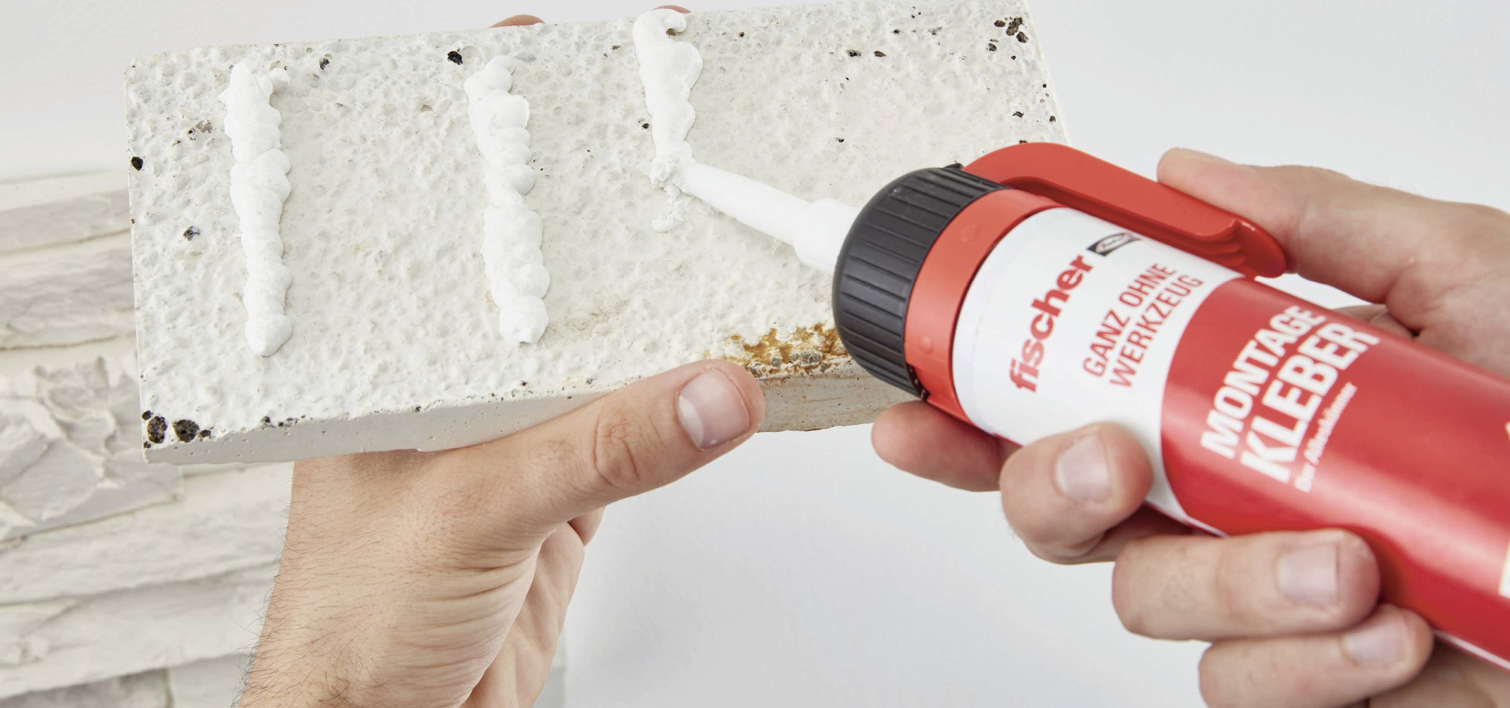 Eine Person hält eine Styroporplatte und trägt mit einer Kleberpistole Montageschaum auf.