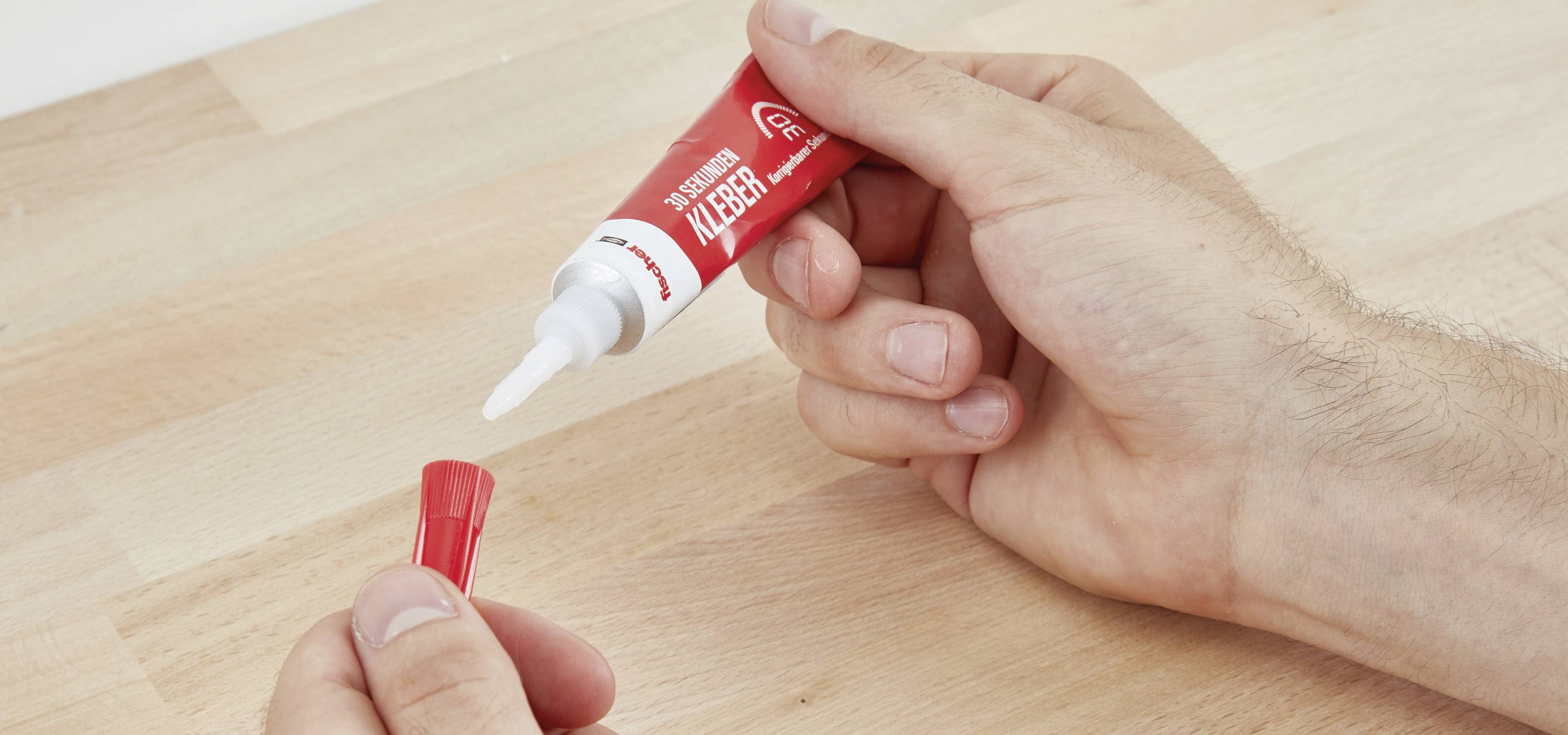 Eine Person hält eine Tube Sekundenkleber in der Hand und öffnet den Verschluss.