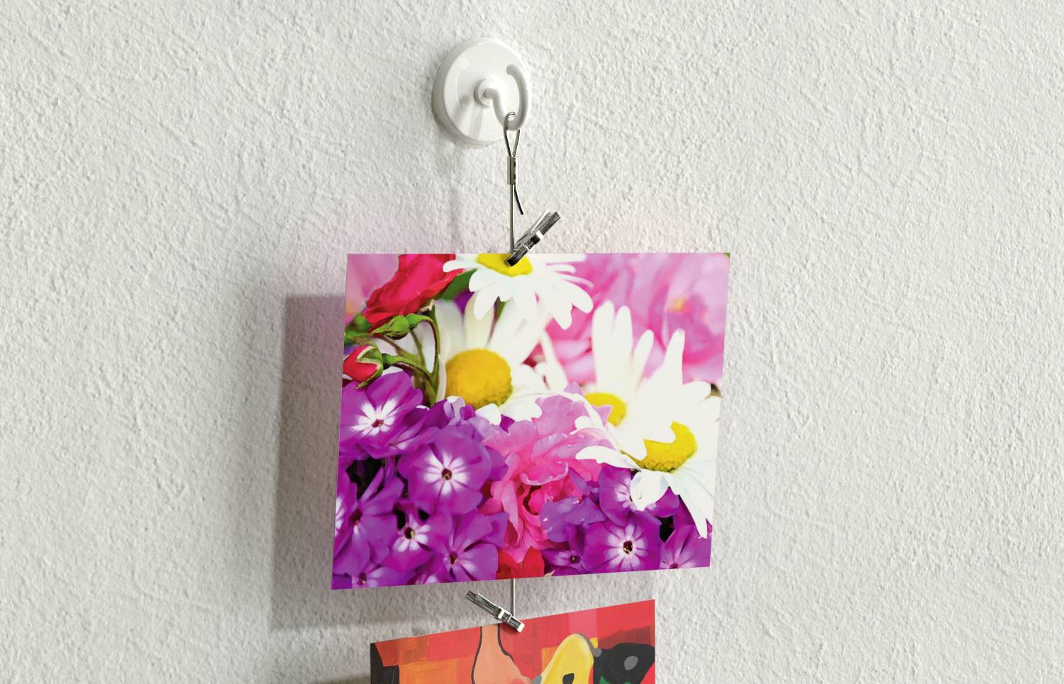 Ein Foto von bunten Blumen, darunter weiße Gänseblümchen und violette Blüten, hängt an einer weißen Wandaufhängung.