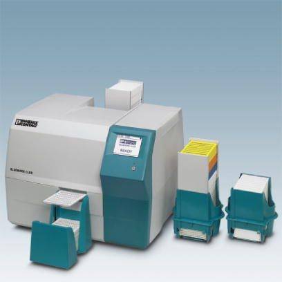 Ein medizinisches Laborgerät mit einem digitalen Display, beschriftet mit 'READY'. Daneben stehen geordnete Probenbehälter.