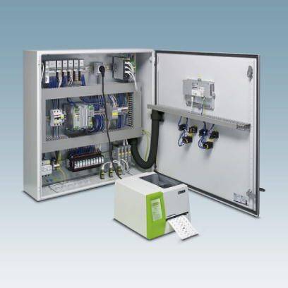 Ein geöffneter Schaltschrank mit elektronischen Komponenten und Kabeln, daneben ein Drucker auf dem Boden.
