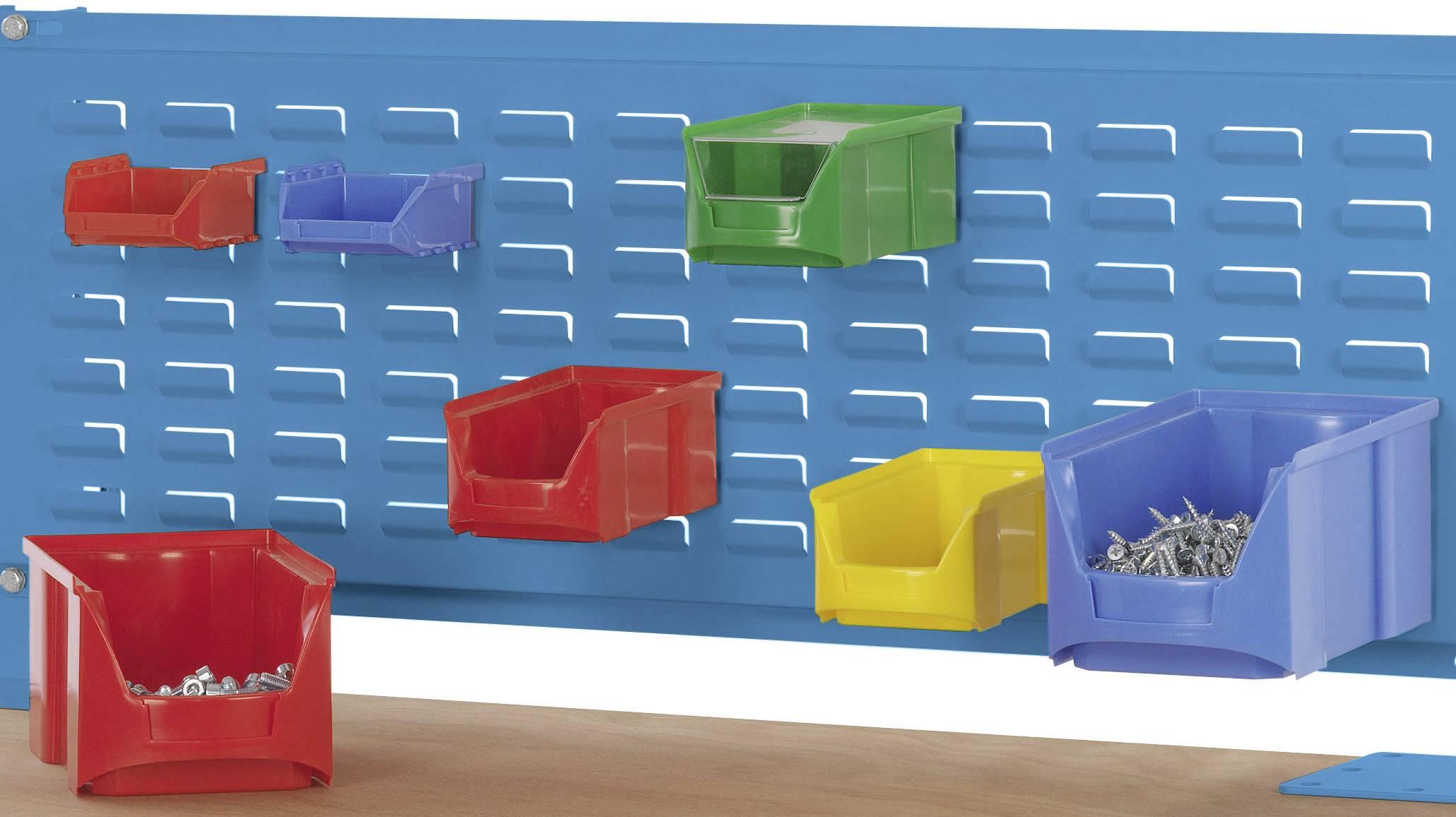 Bunte Aufbewahrungsboxen an einer blauen Gitterwand, gefüllt mit Schrauben und kleinen Teilen, hängen über einer Werkbank.