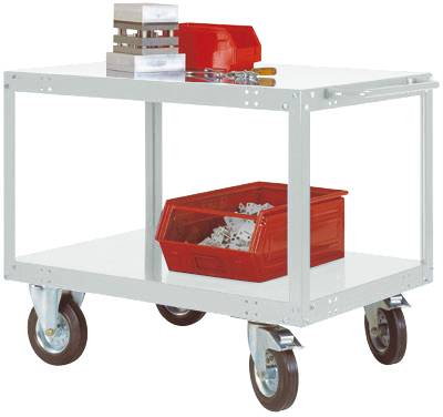 Ein weißer Werkstattwagen mit vier Rädern. Auf dem oberen Regal liegt ein roter Werkzeugkasten und Metallblöcke, auf dem unteren Regal eine rote Box mit Papierstücken.
