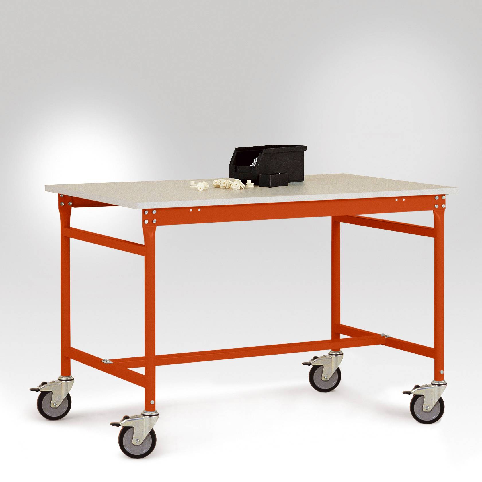 Ein roter Arbeitstisch auf Rollen mit grauer Tischplatte. Auf dem Tisch stehen eine schwarze Werkzeugbox und lose Schrauben.