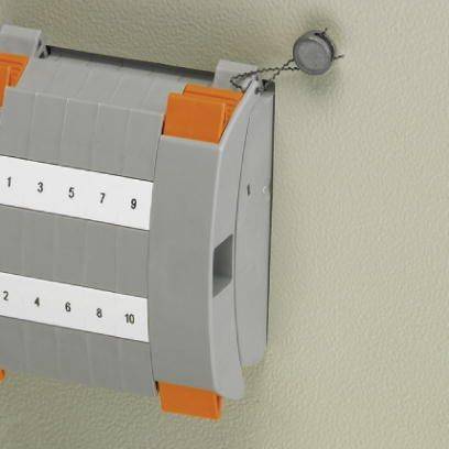 Ein grauer Kabelmarkierer mit den Zahlen 1 bis 10 in schwarz, montiert an einer Wand mittels einer Schraube und Kordel.